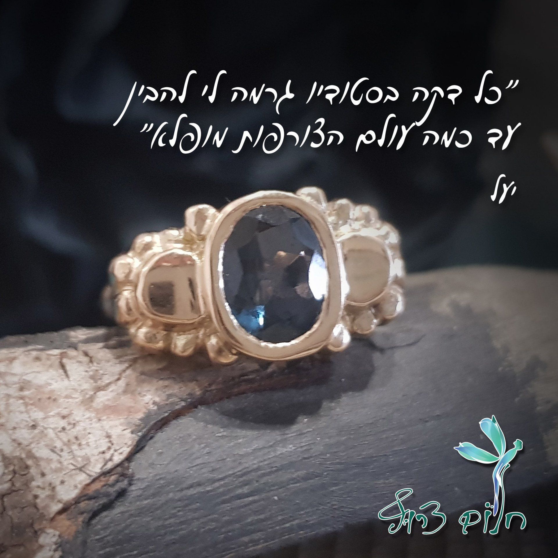 טבעת זהב עם אבן כחולה יושבת על פיסת עץ