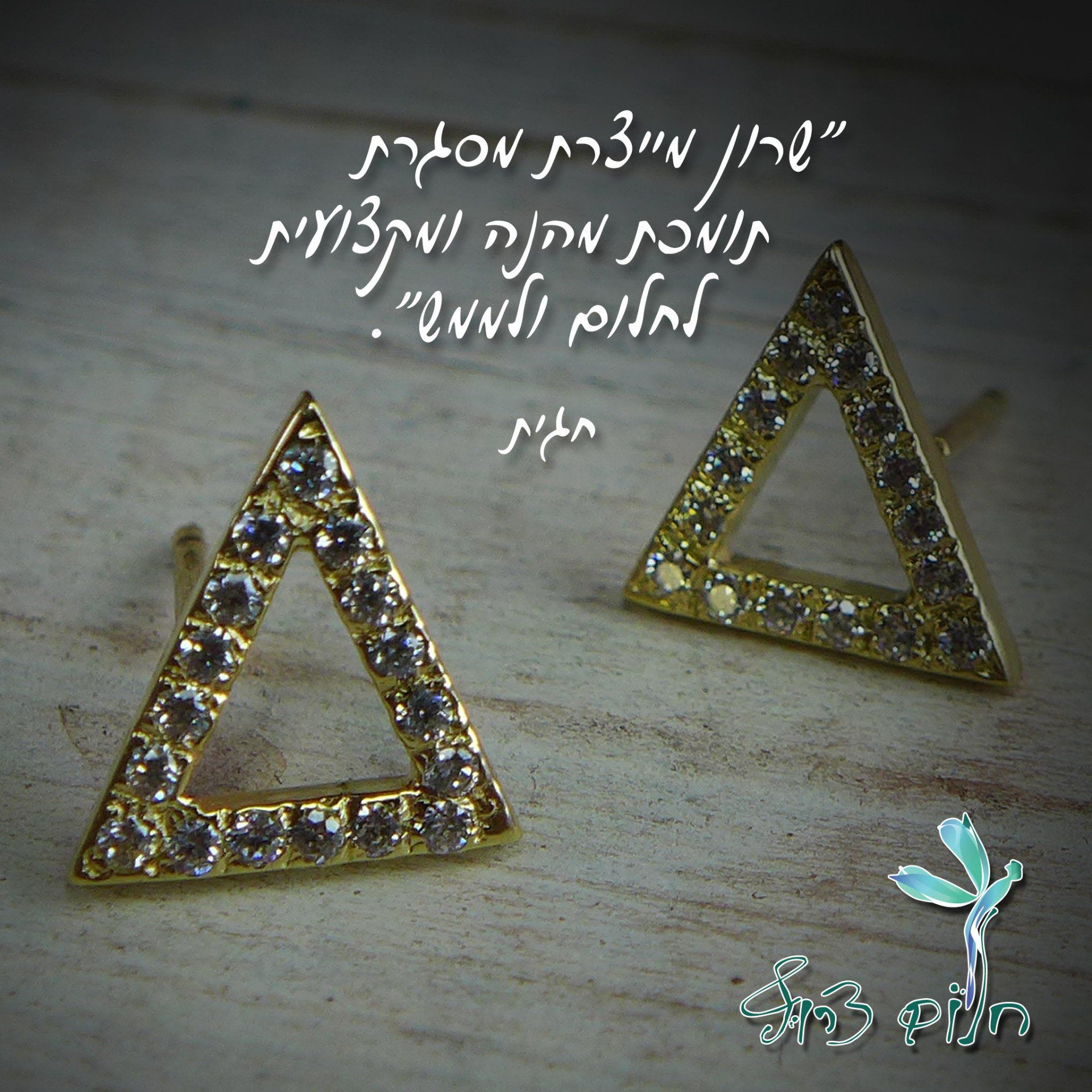 זוג עגילי זהב משולשים על משטח עץ