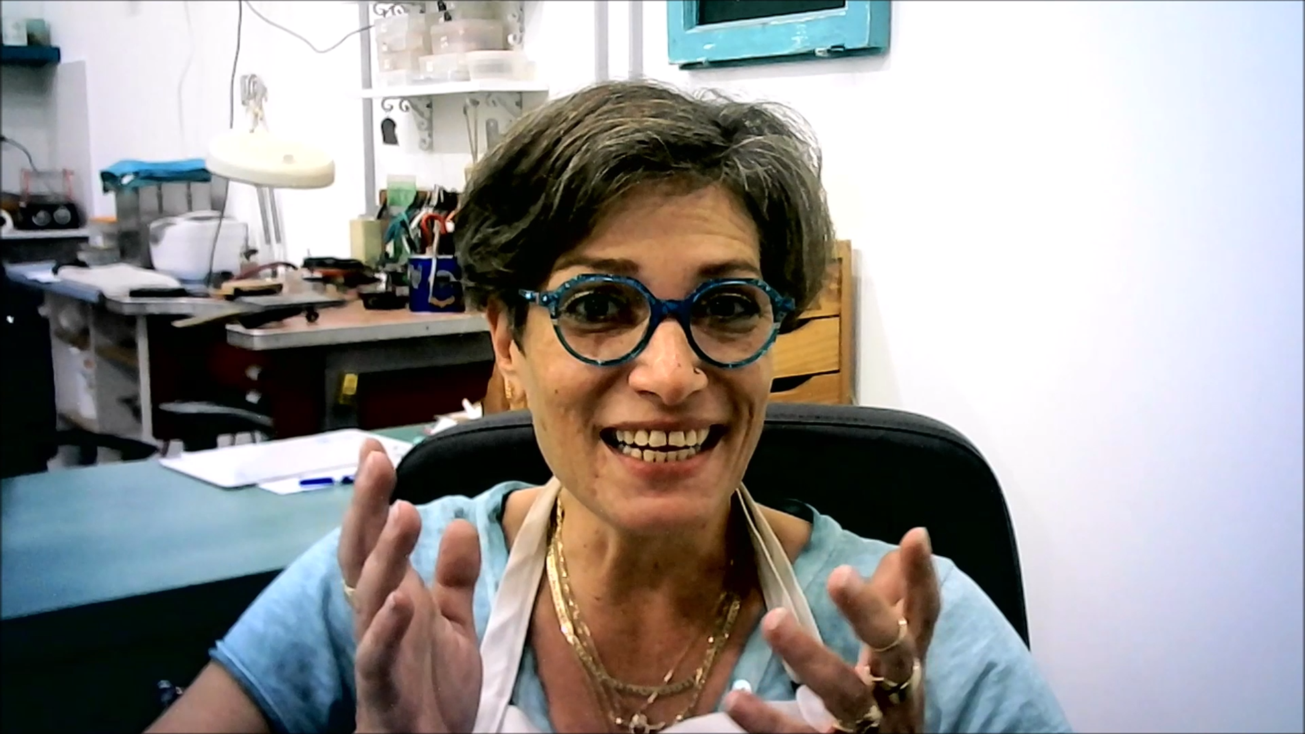 אישה מרכיבה משקפיים יושבת על כיסא ומחייכת