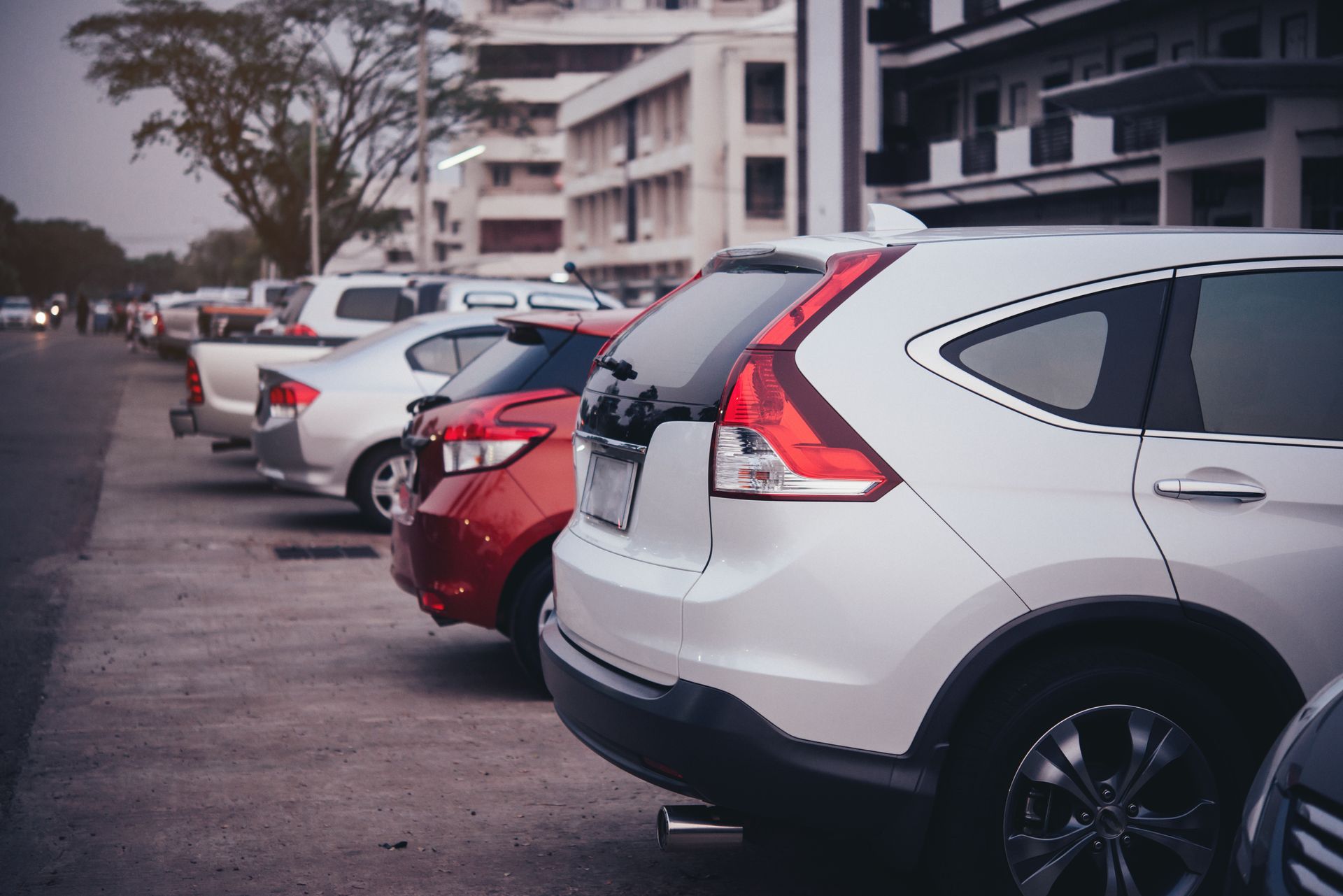 A row of cars are parked next to each other in a parking lot.