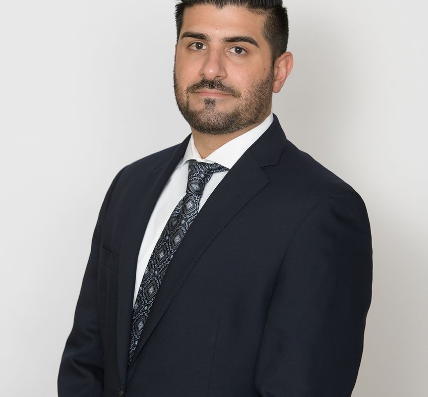 Man in navy suit and patterned tie, posing for a professional headshot.