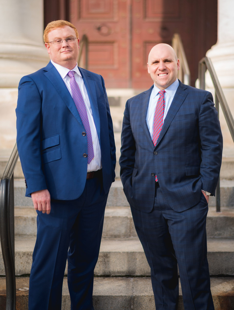 BBB Atorneys Peter Billings and Peter Bowman in suits standing on steps outside a building