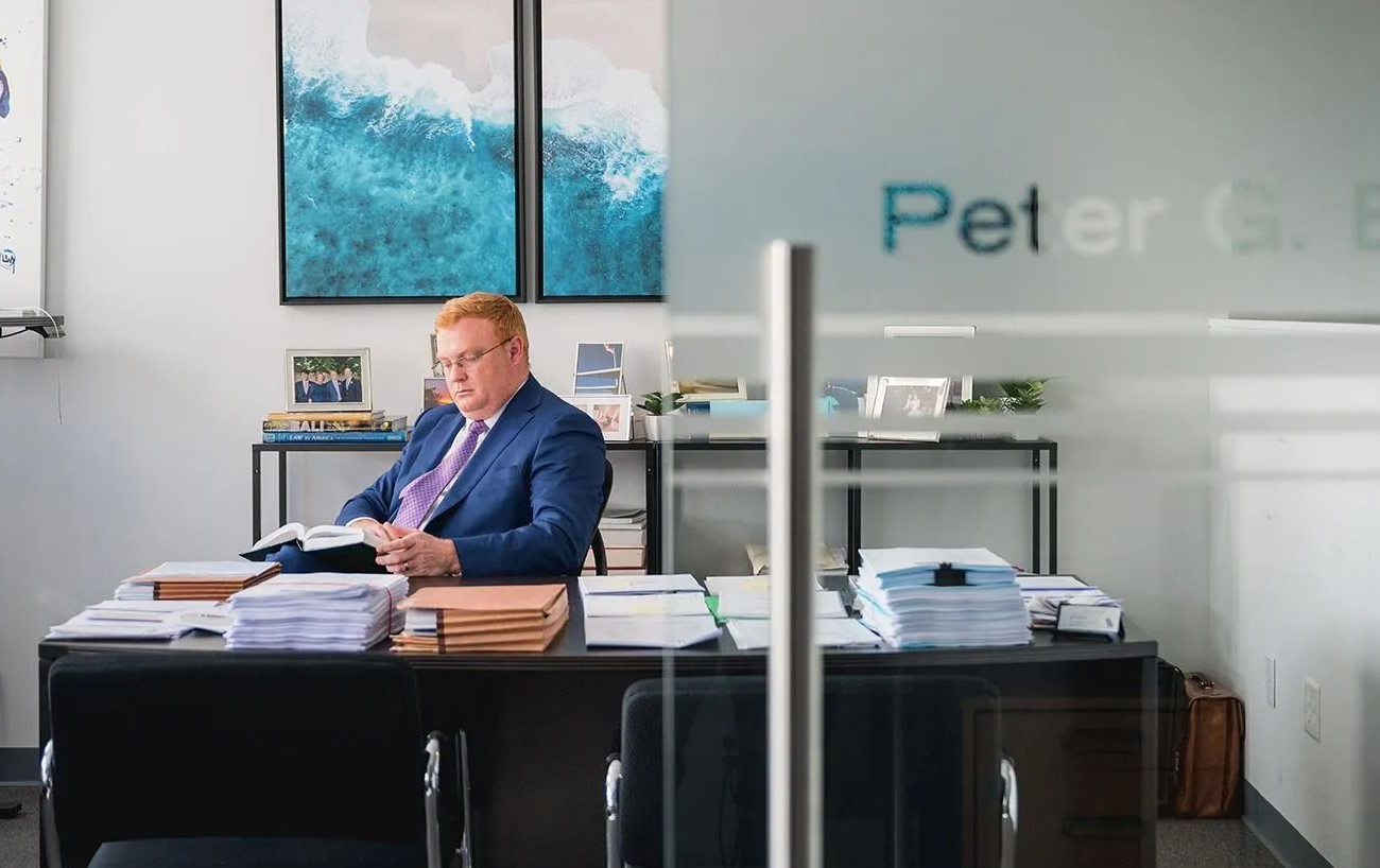 Man sitting at a desk in a modern office with papers and blue wall art behind him