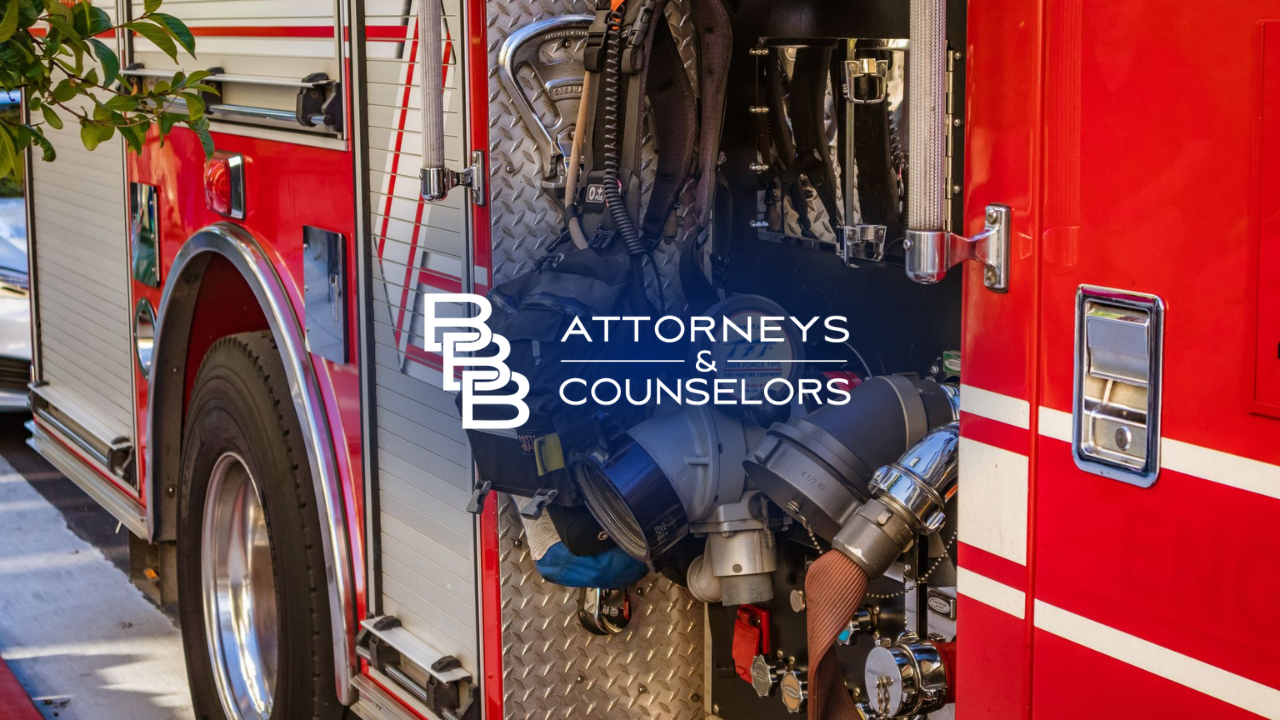 Red fire truck with “Attorneys & Counselors” logo and hoses in an open compartment