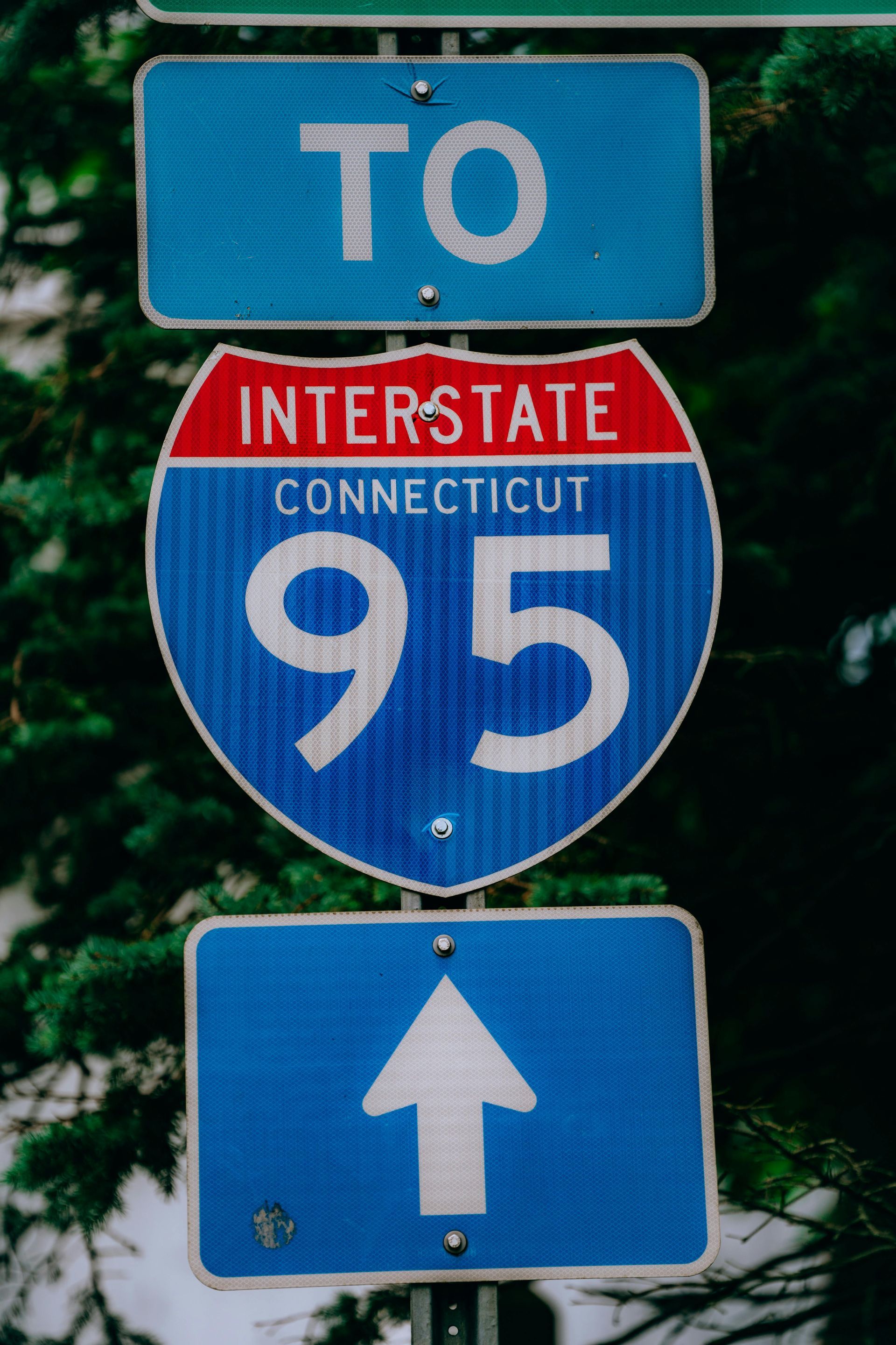 Road signs for Interstate 95 in Connecticut with a “TO” sign and upward arrow.