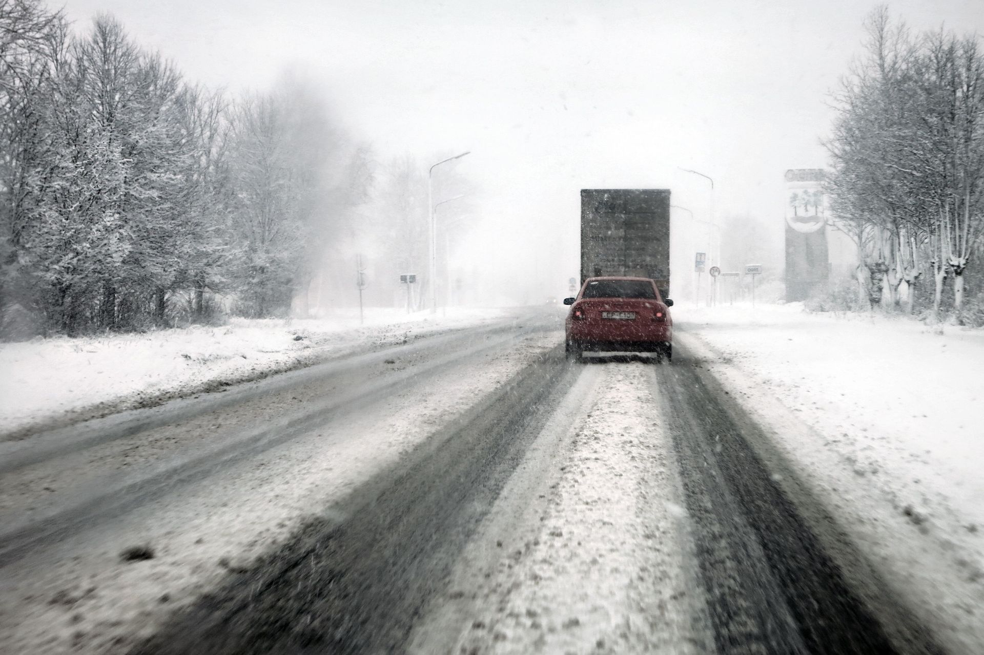 Truck driving on a snow-covered road in a heavy winter storm