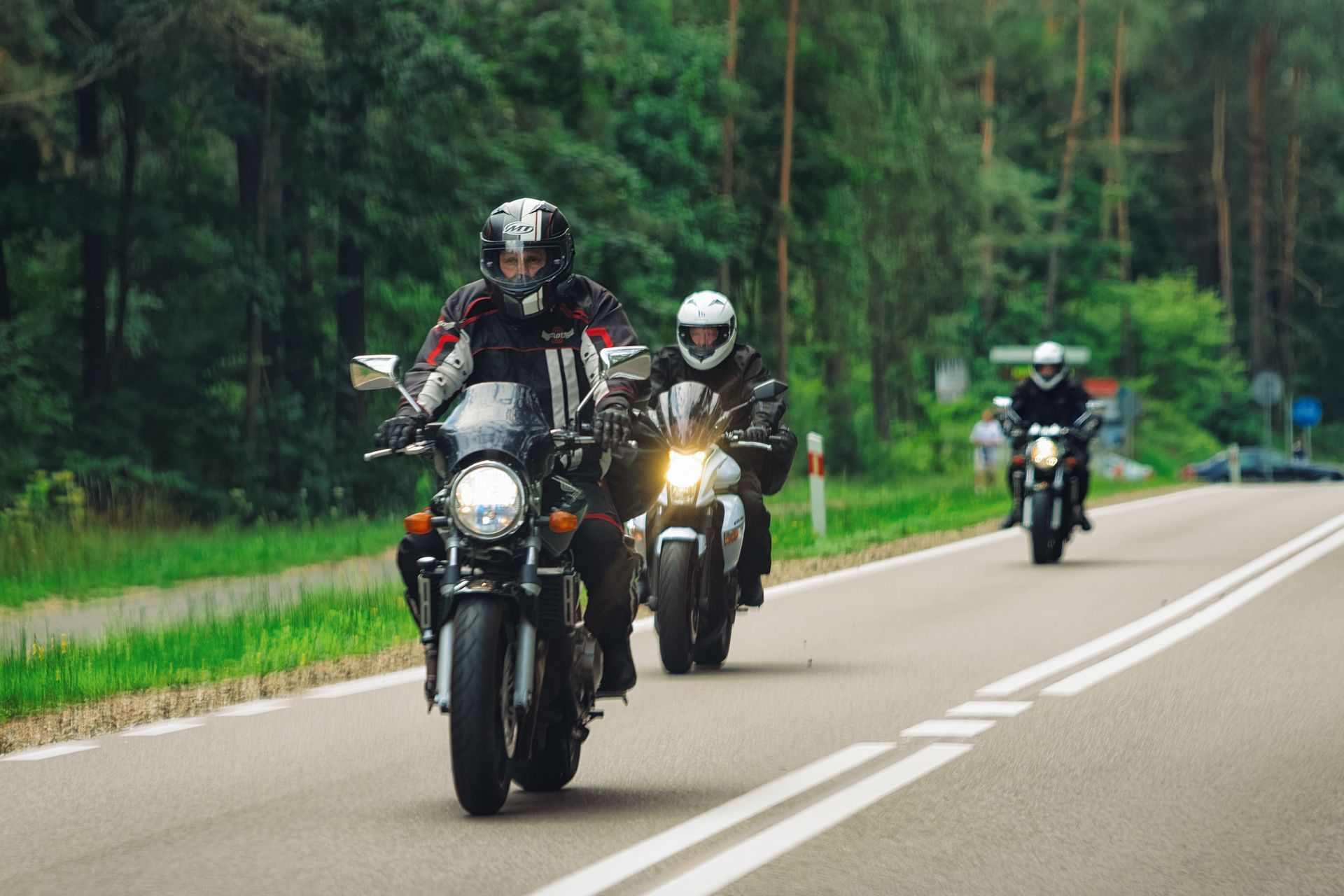 Motorcyclists struggle through a muddy off-road hill climb, with several bikes stuck on the slope.