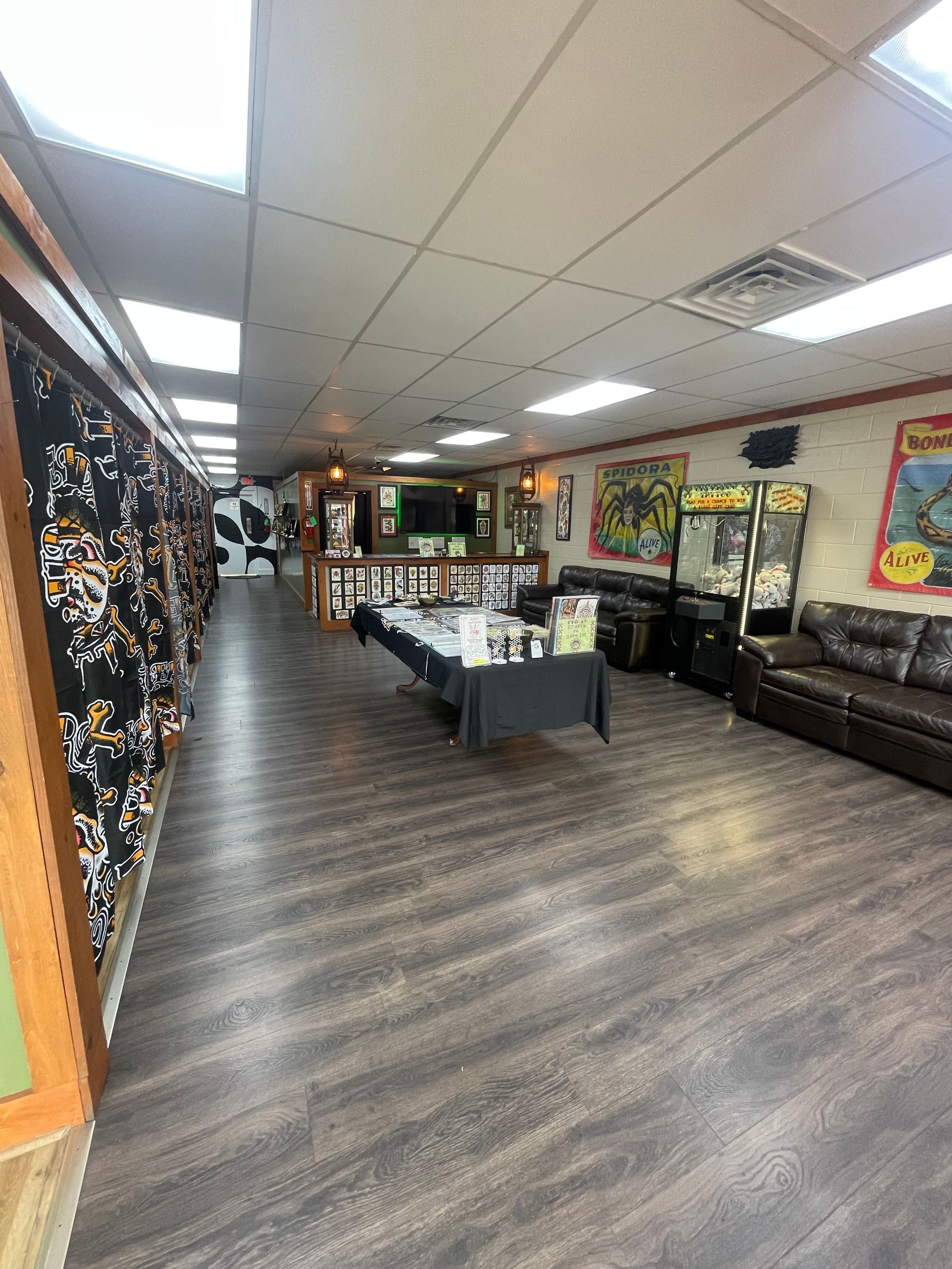 Lobby with gray wood flooring, black couches, coffee table, and colorful wall art under bright ceiling lights
