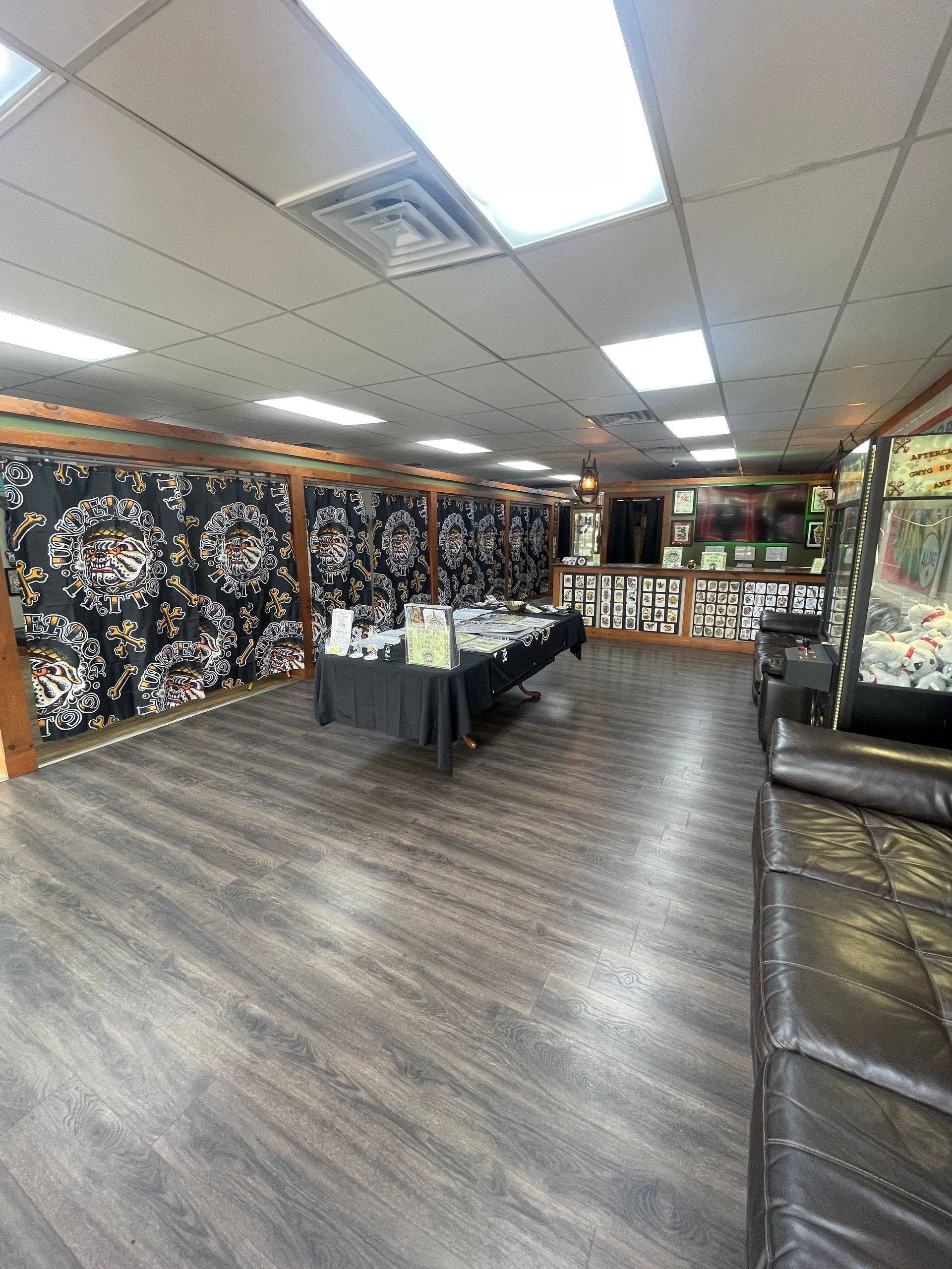 Empty event room with patterned black walls, wood flooring, folding tables, and bright ceiling lights.