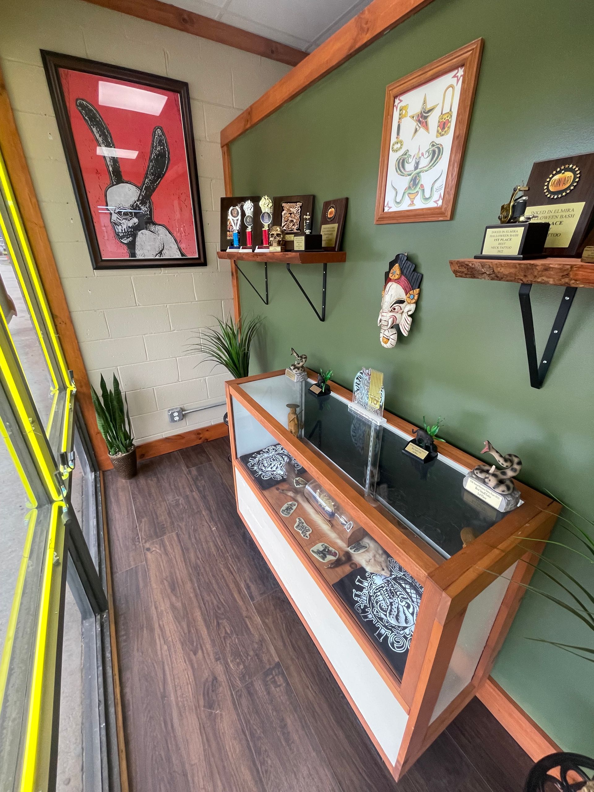 Small shop display area with wooden cases, green walls, shelves of bottles, and a red poster