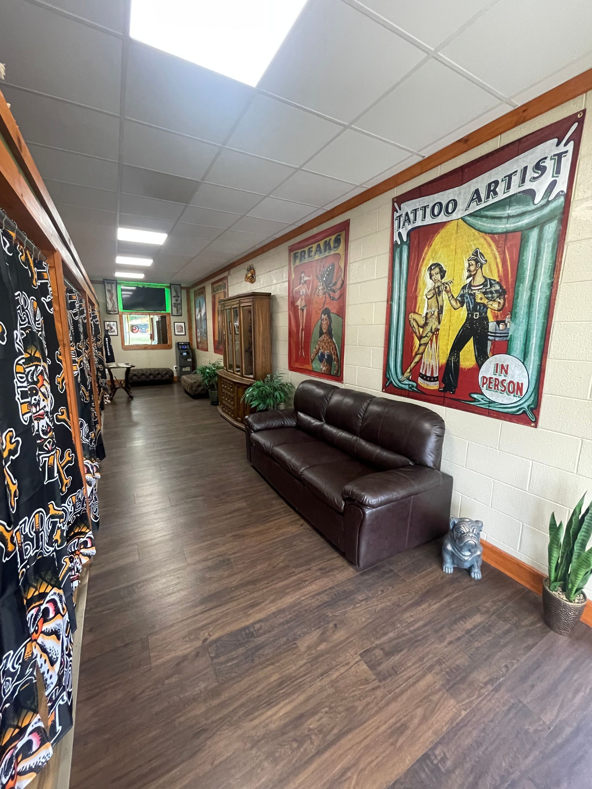 Long hallway with dark wood floor, leather sofa, and colorful posters on the walls