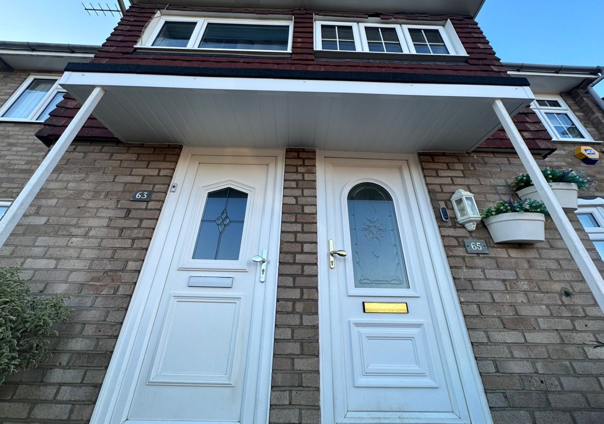 Two white front doors under a porch, brick facade, windows above.