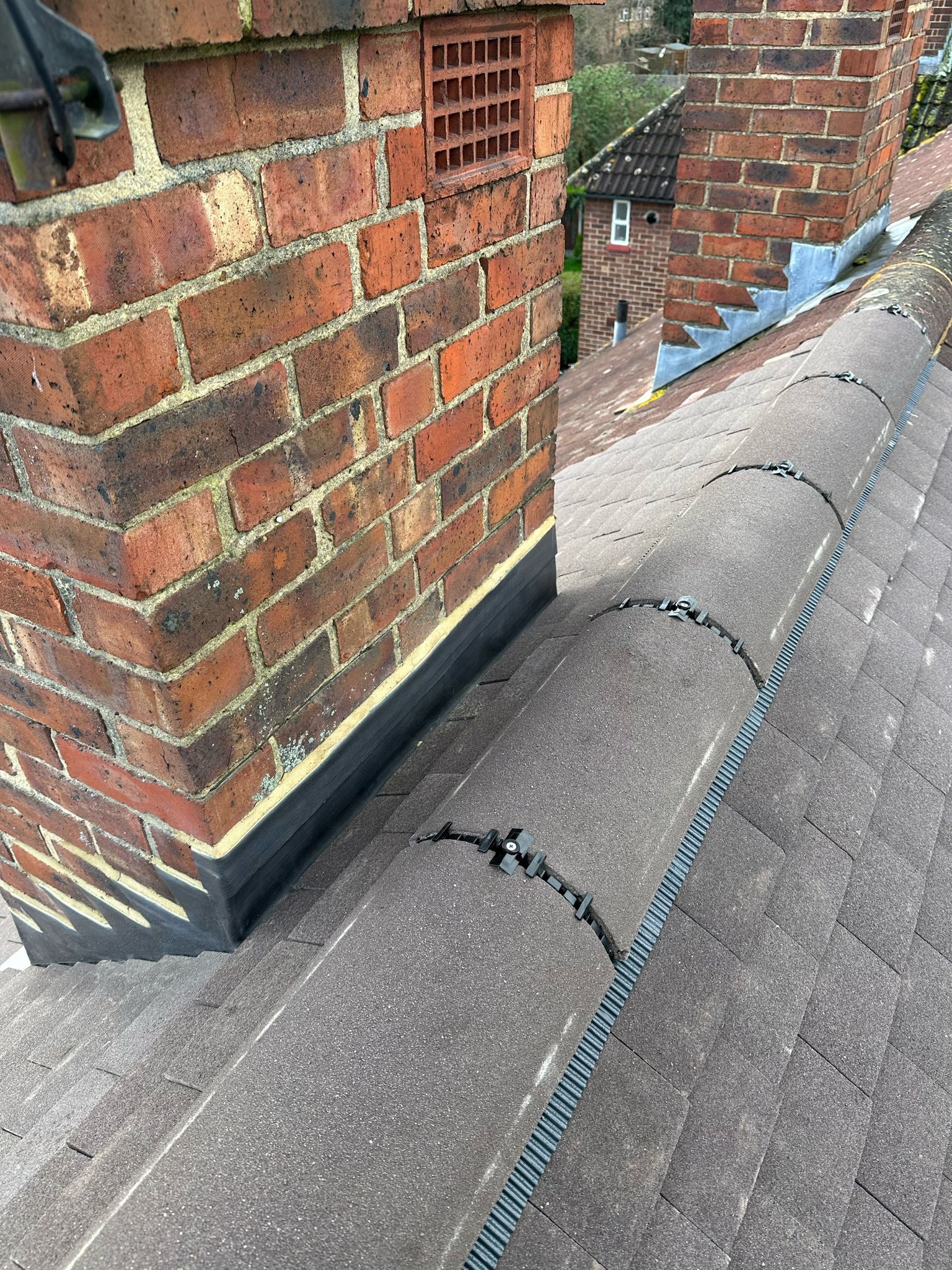 Brick chimney on a tiled roof, showing flashing.