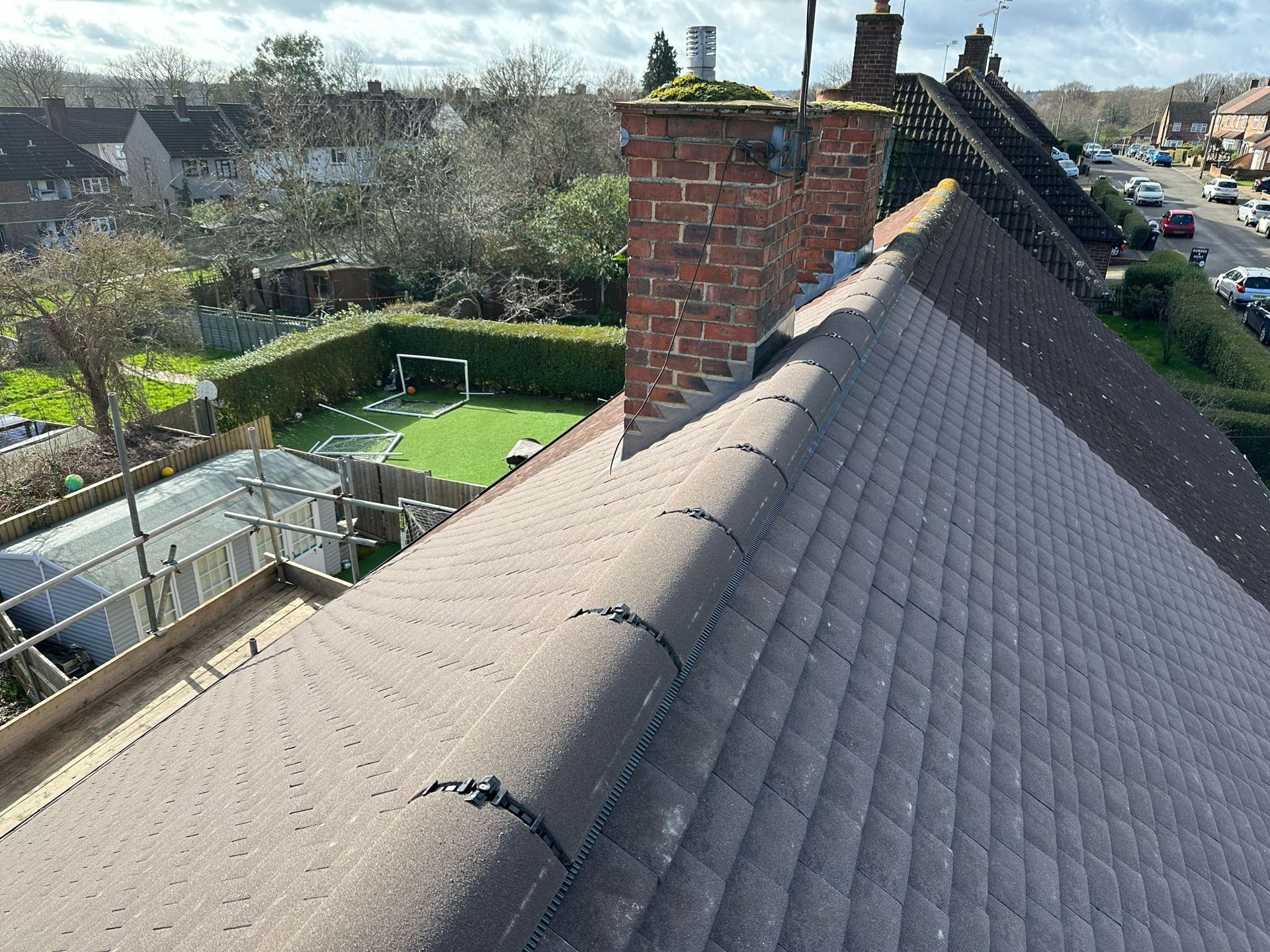 A house roof with a brick chimney and street view in the background.
