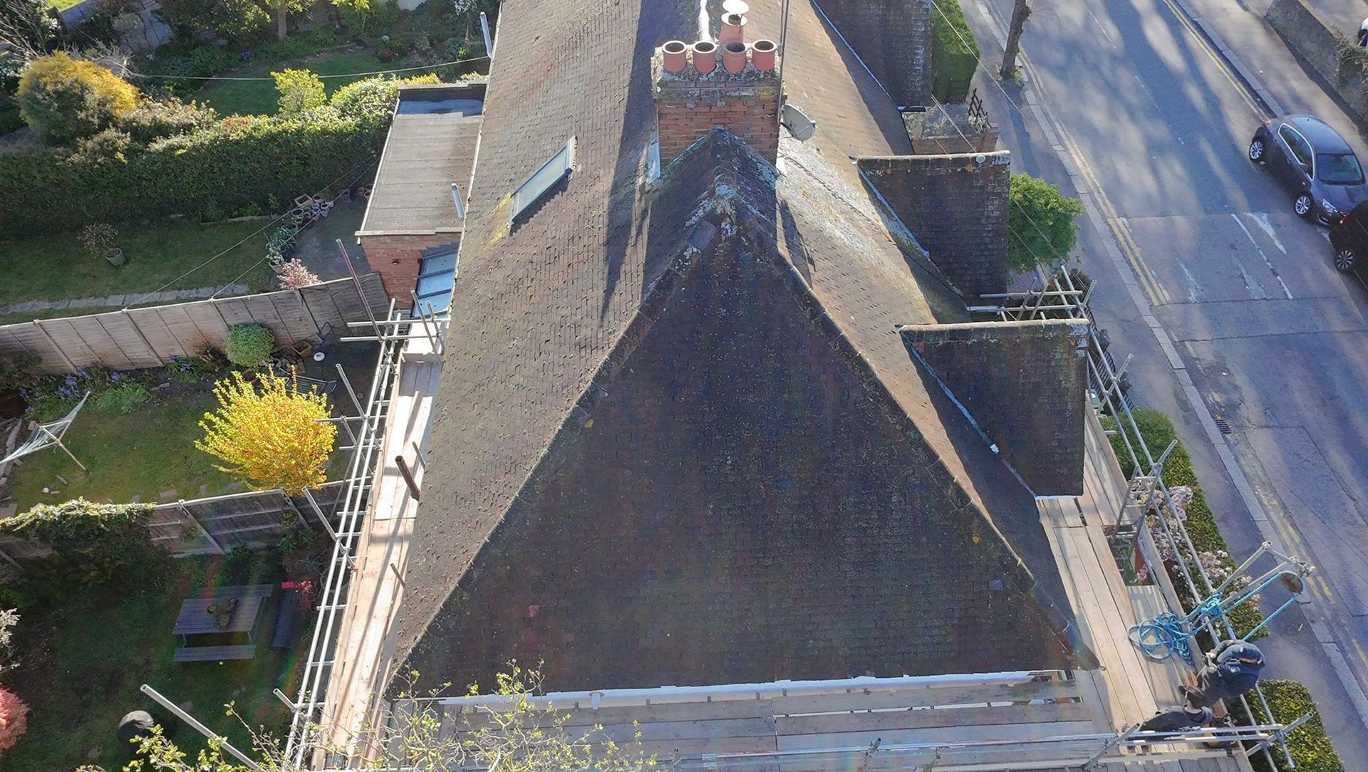 Aerial view of a large slate-roofed house beside a road and garden.