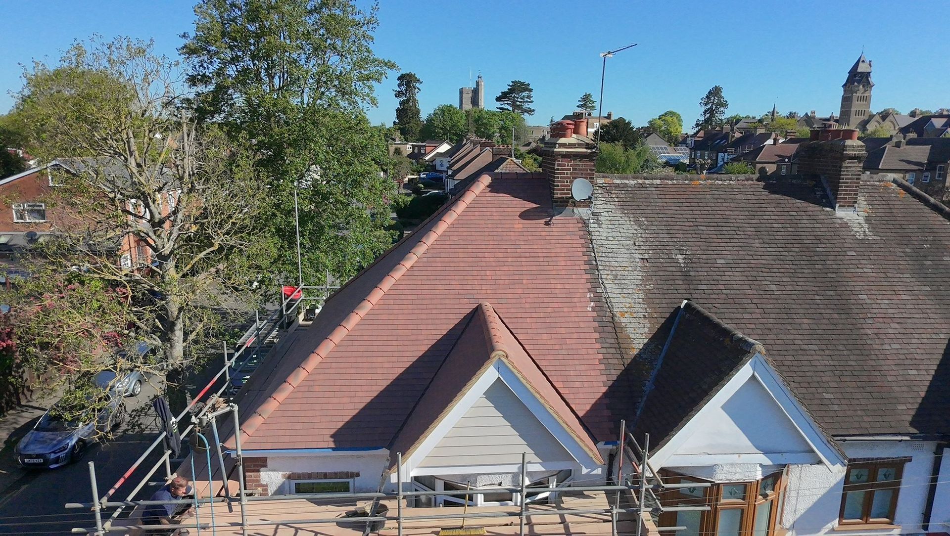 Rooftops under a clear blue sky, with trees and brick chimneys in a residential neighborhood