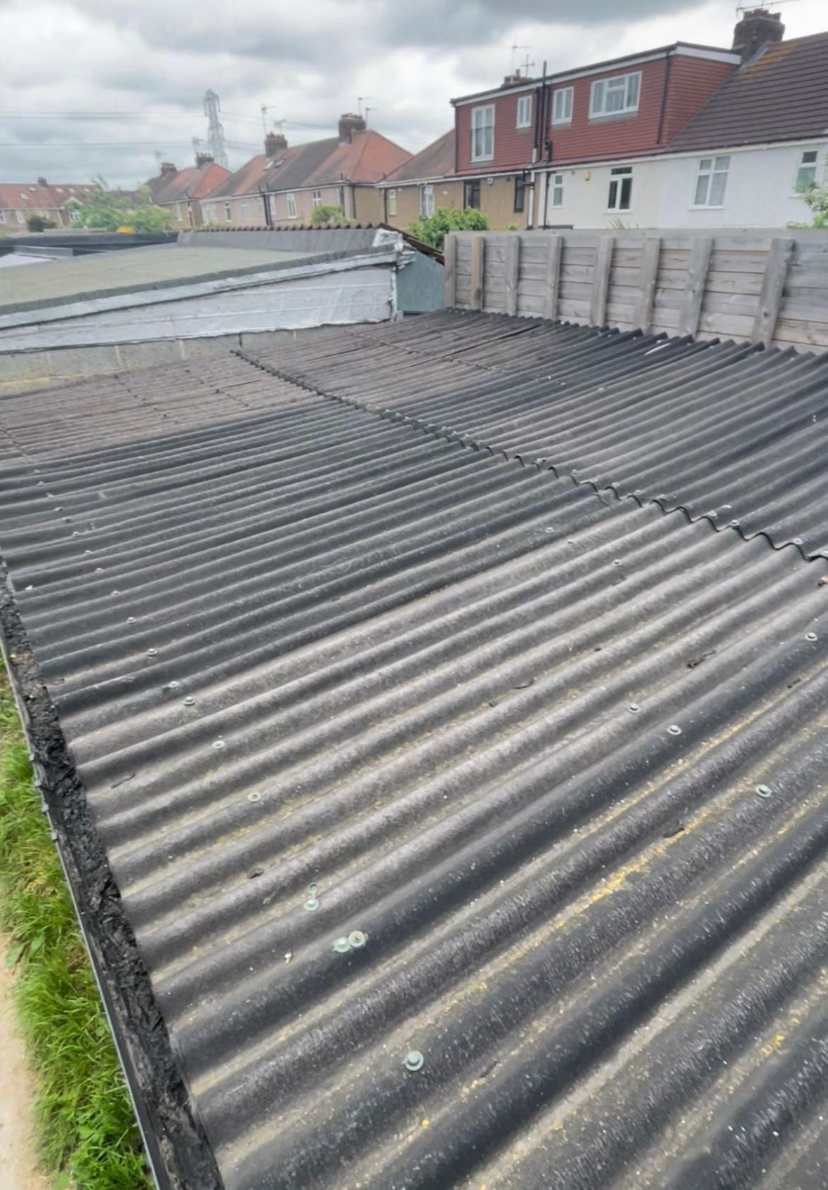 Corrugated, dark roof with adjacent houses visible in a residential area.