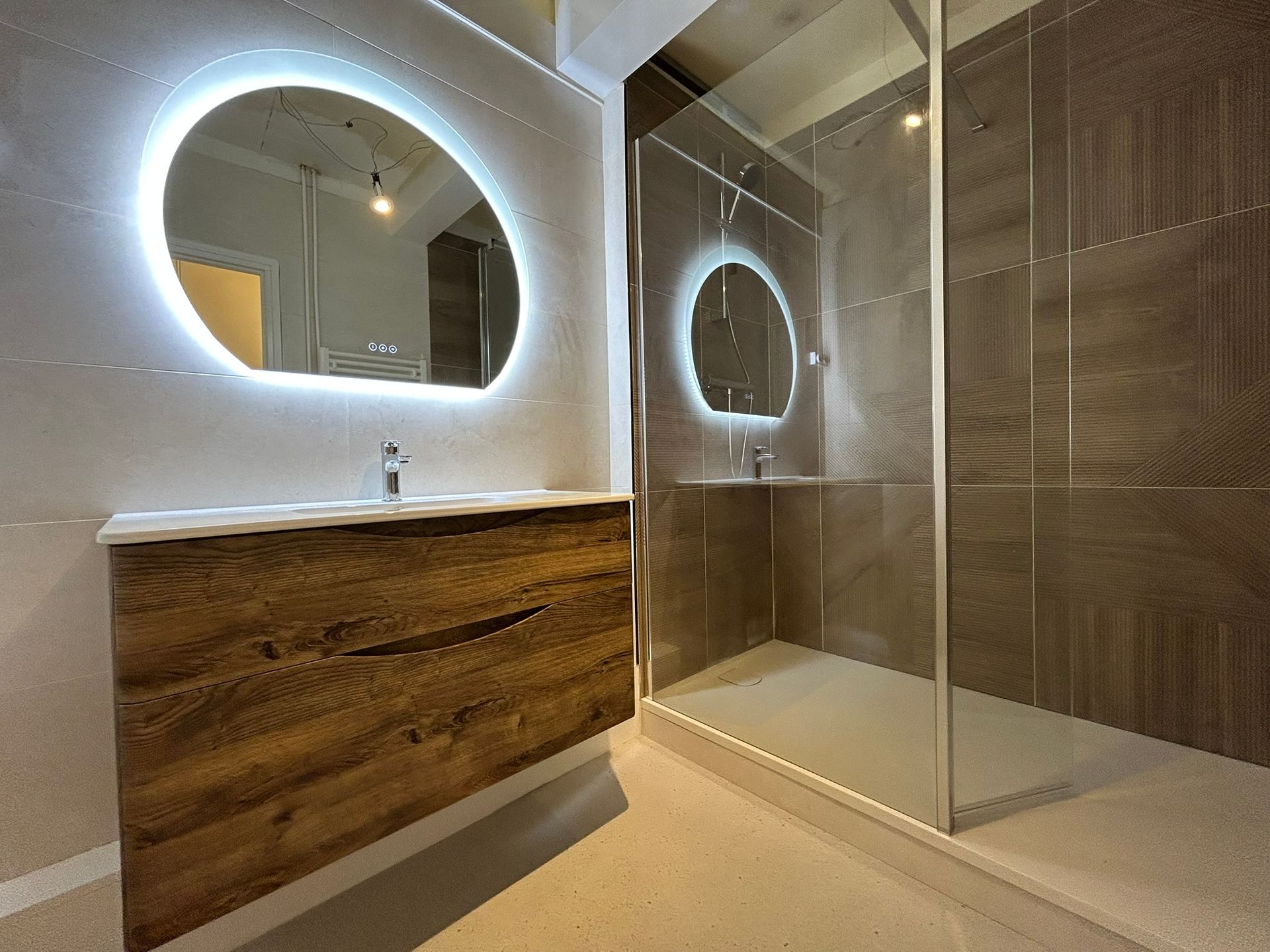 Salle de bain avec lavabo miroir rond et douche à l'italienne