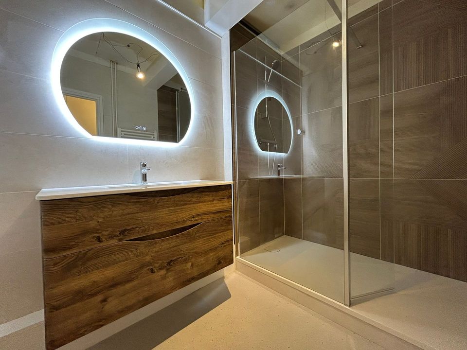Salle de bain Isla au Havre : meuble vasque chêne foncé, miroir demi-lune rétroéclairé et douche à paroi vitrée