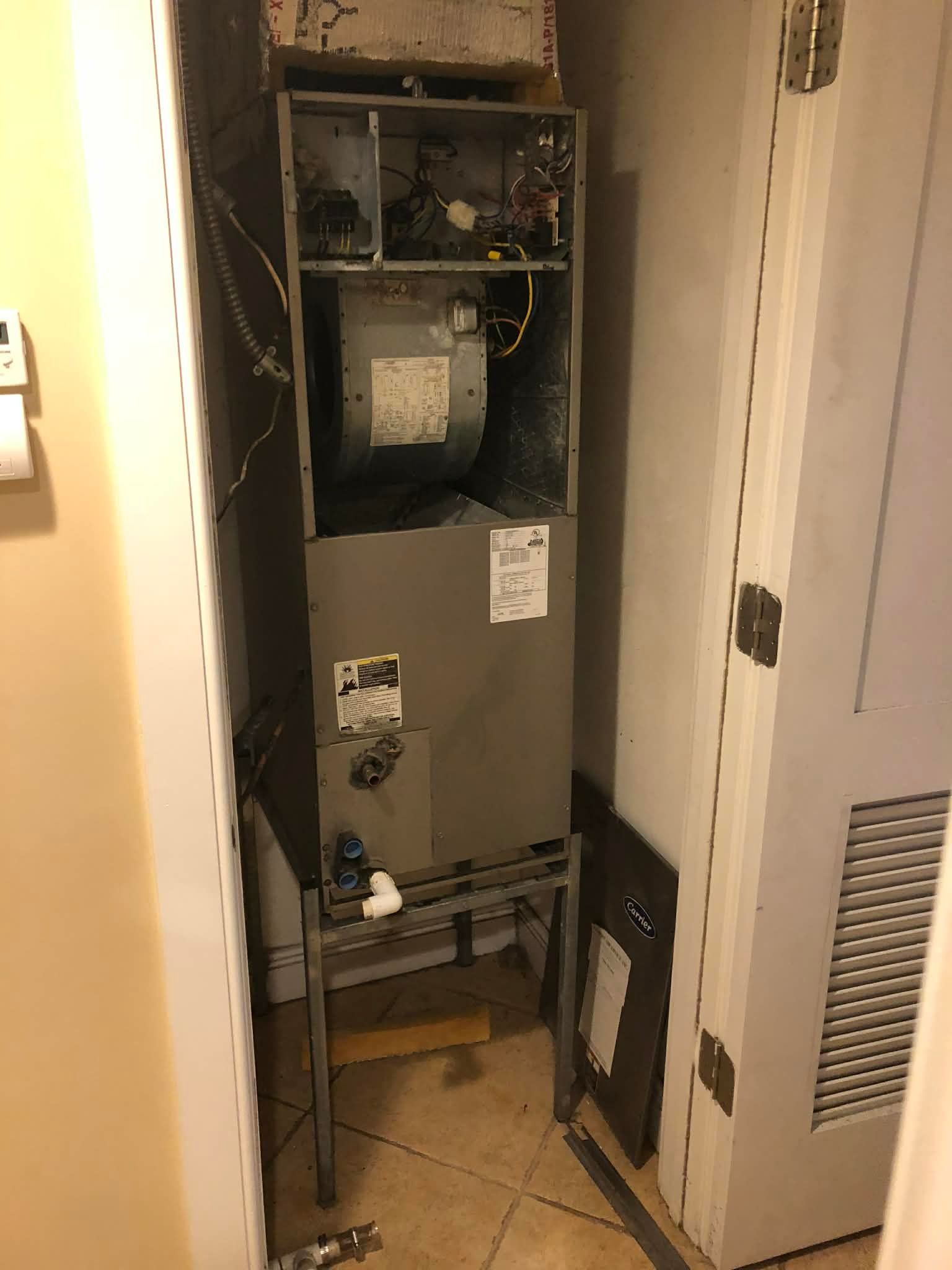 Open utility closet with exposed furnace and HVAC equipment inside a narrow hallway.