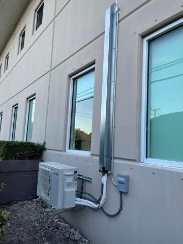 Three rooftop HVAC units on a metal support frame beside a building