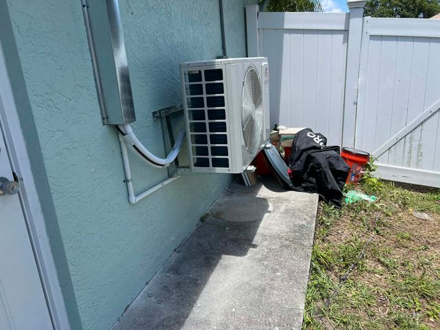 Technician inspecting an outdoor air conditioner unit with the top panel open