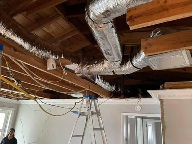 Industrial HVAC unit with ducts, control panel, and red hoses in a utility room