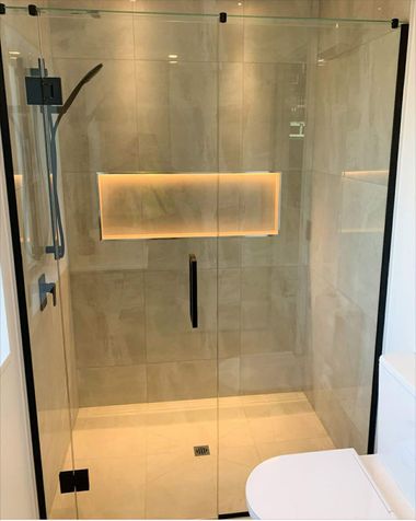 Glass shower with backlit recessed shelf in a modern bathroom