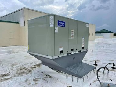 Large gray HVAC unit on a metal platform in a snowy outdoor industrial area