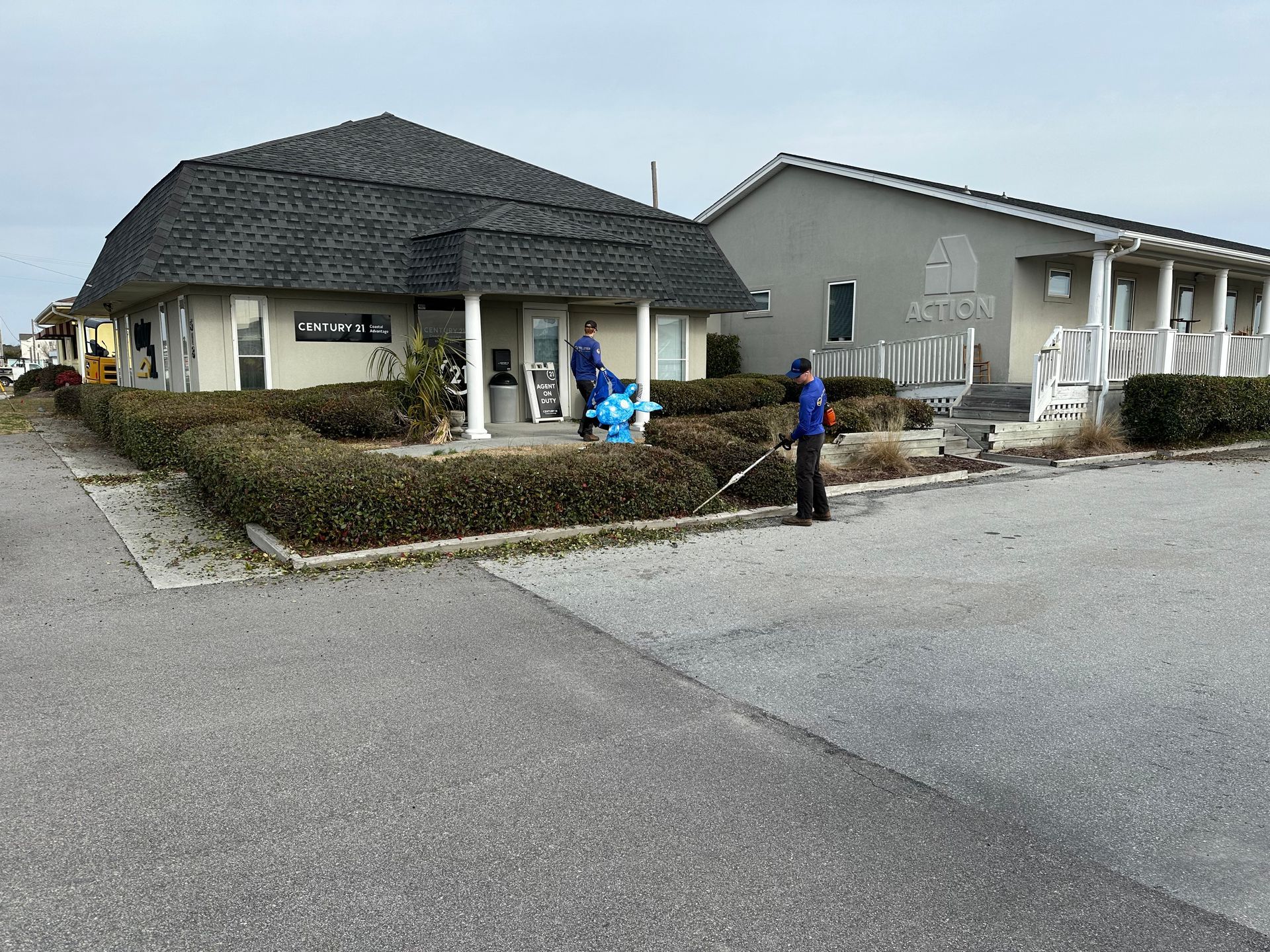 A man is sweeping the sidewalk in front of a building.