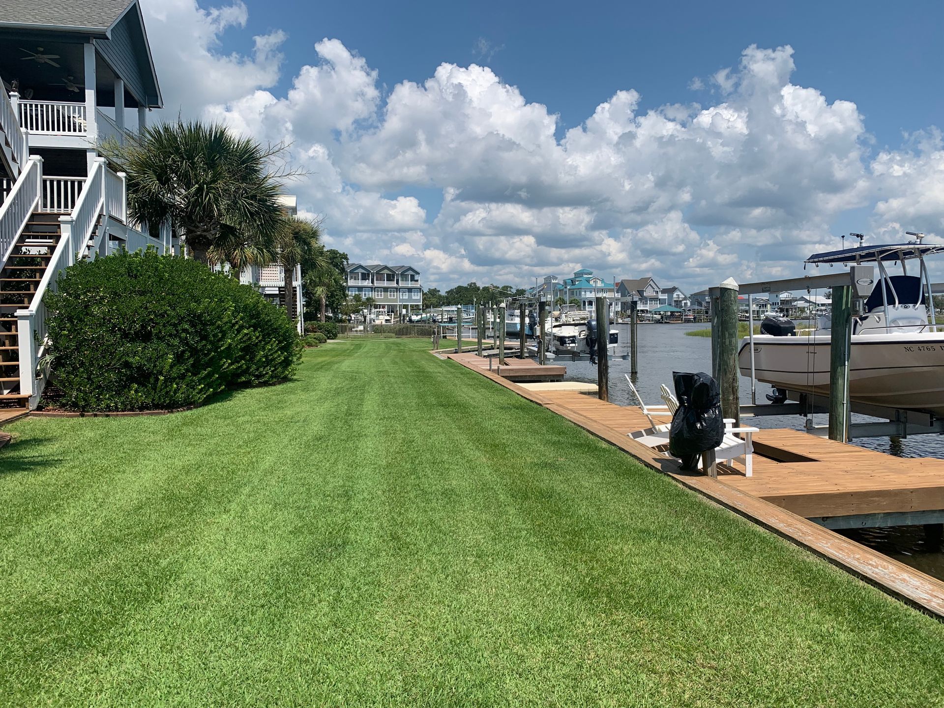 A dock with boats docked next to a house and a lush green lawn.