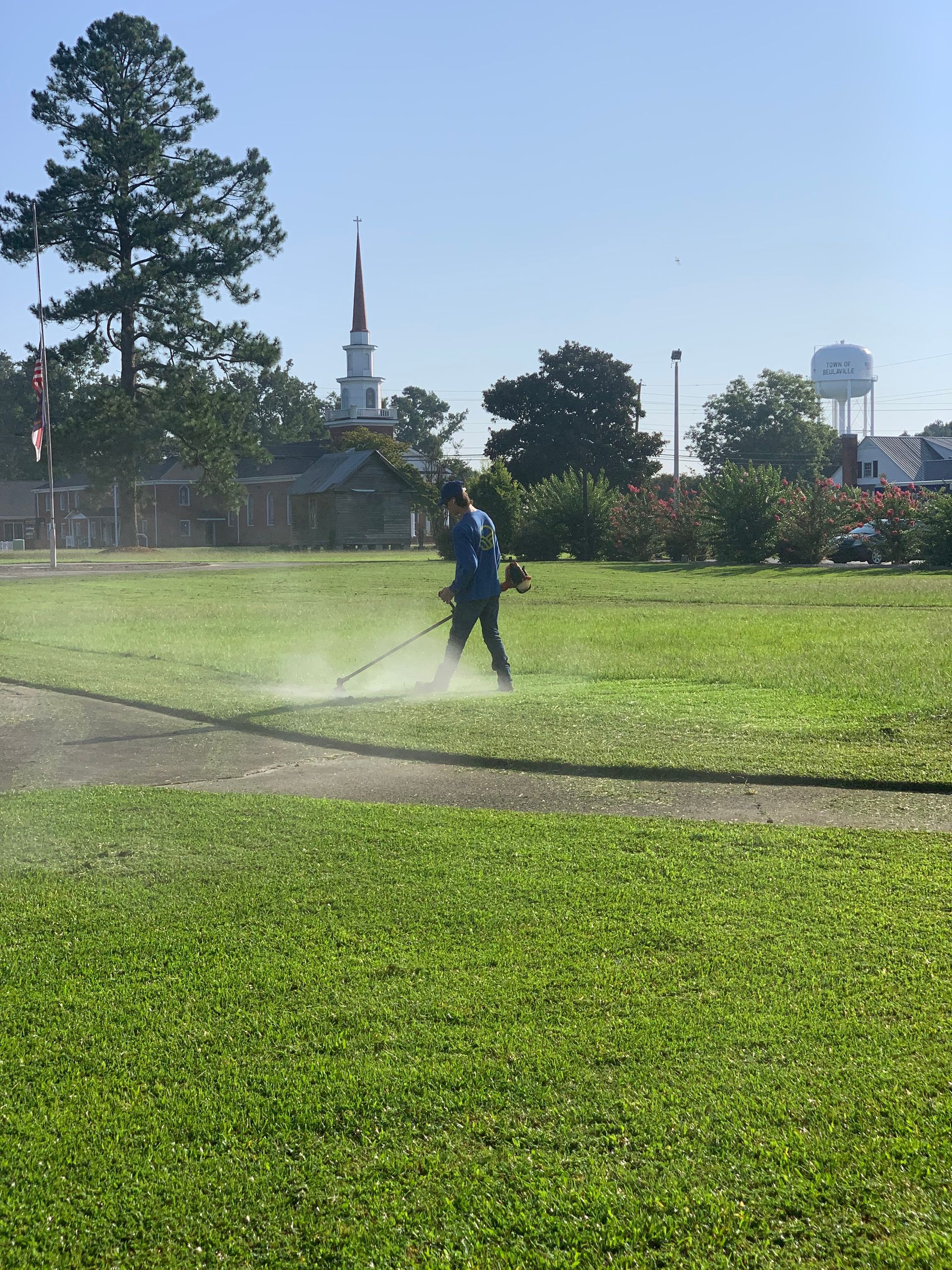 A man is mowing a lush green field with a lawn mower.