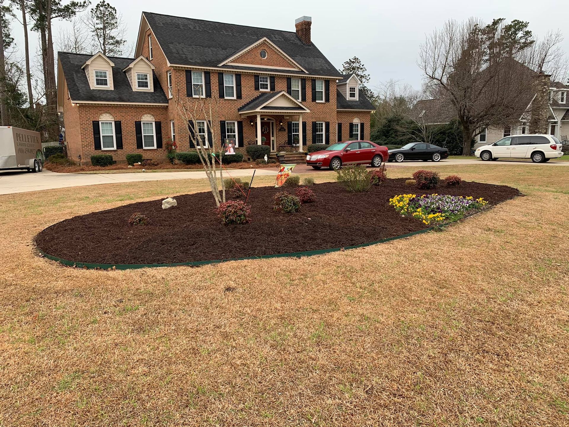 A large brick house with a lush green lawn in front of it.