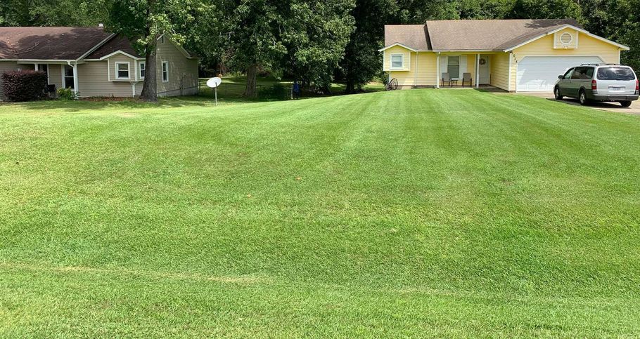 A house with a large lawn in front of it and a car parked in front of it.