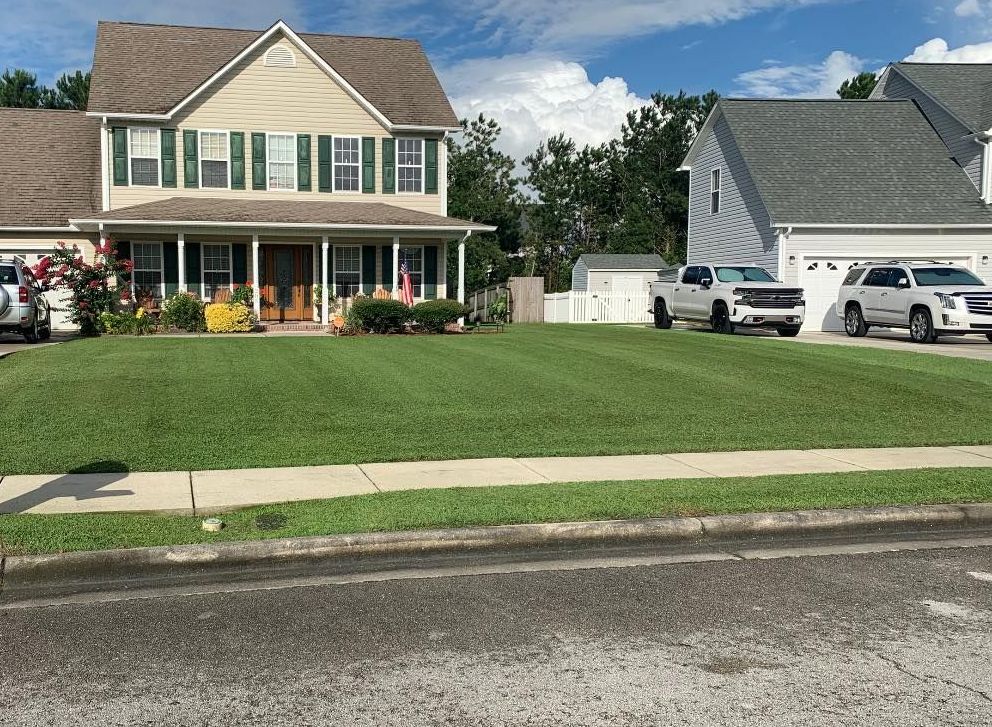 A house with a large lawn in front of it and a car parked in front of it.