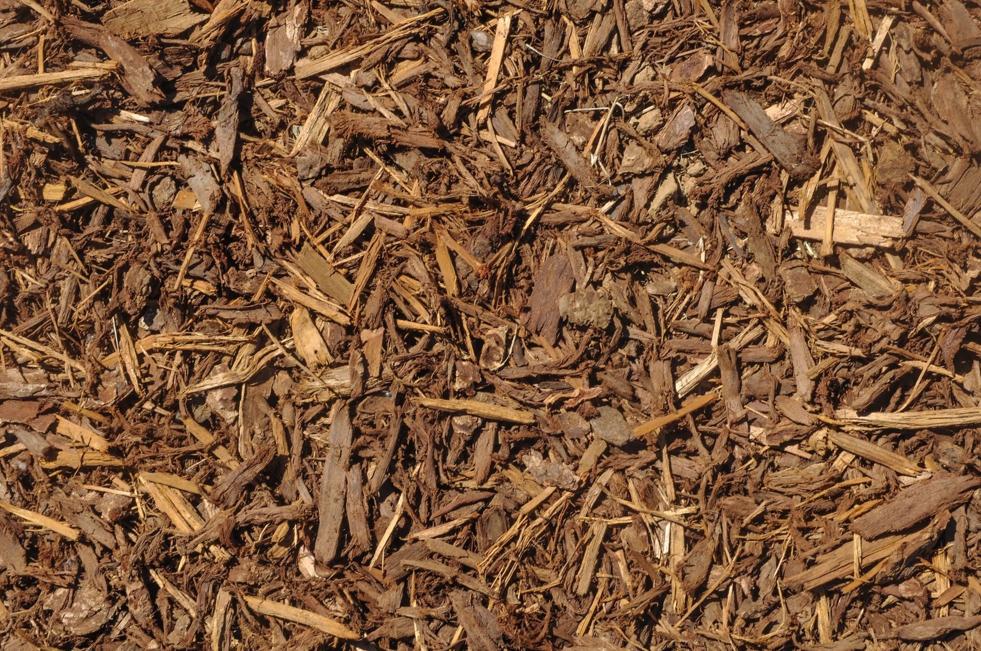 A pile of brown mulch is sitting on the ground.