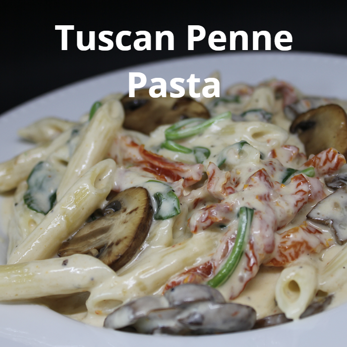 A delicious plate of Tuscan Penne Pasta, featuring penne pasta with a creamy sauce made from butter, heavy cream, freshly grated Parmesan cheese, and finely chopped garlic, mixed with julienned sundried tomatoes, sautéed cremini mushrooms, and baby spinach leaves, garnished with chili flakes and freshly ground black pepper.