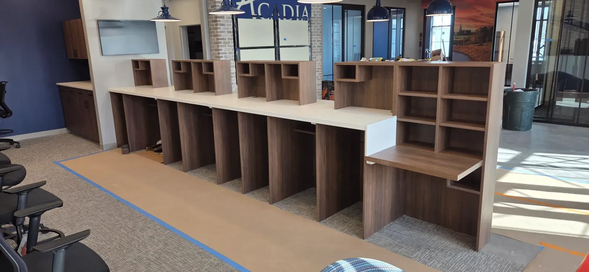 Wooden cubby-style shelving unit in an indoor office or school lobby, with computers and chairs nearby.