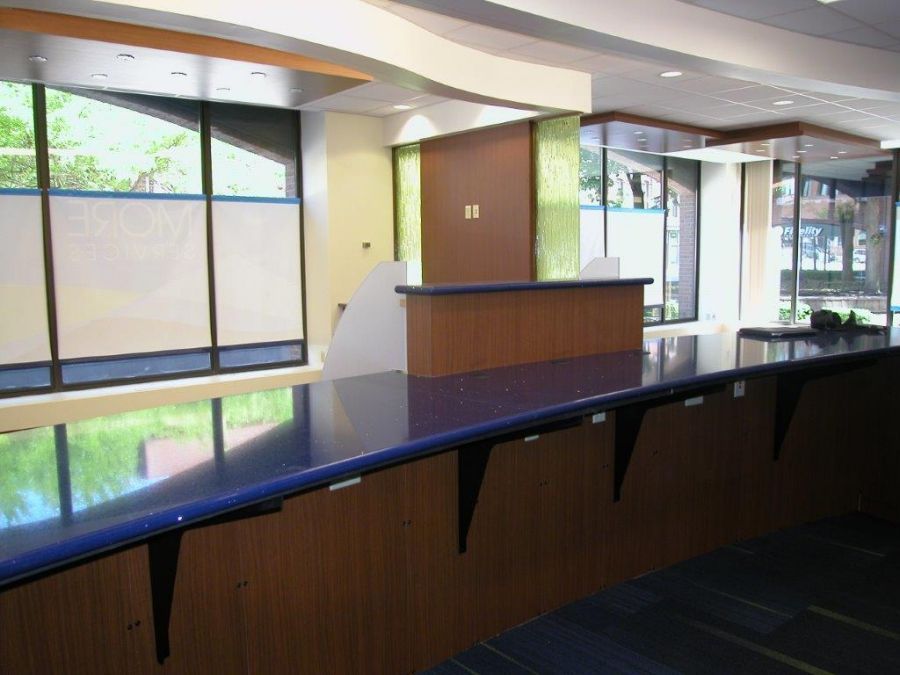 Empty modern lobby with a curved dark counter, wood paneling, and large windows letting in daylight