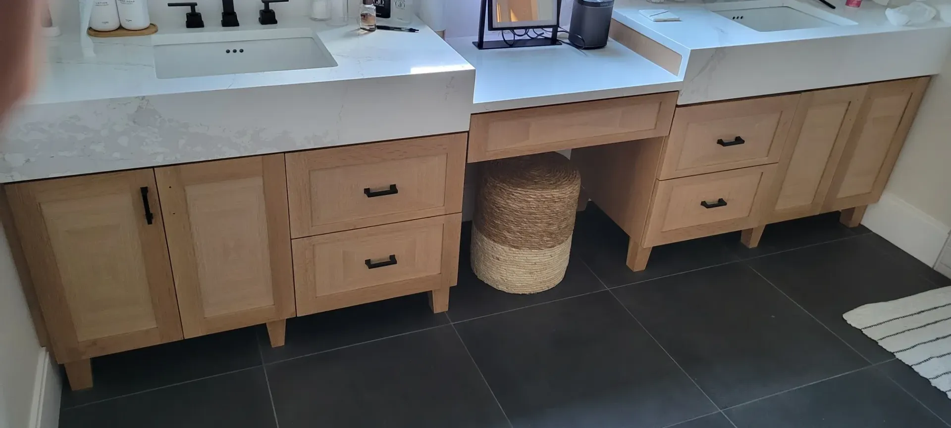 Kitchen cabinets with light wood doors, white countertop, drawers, and a woven basket underneath.
