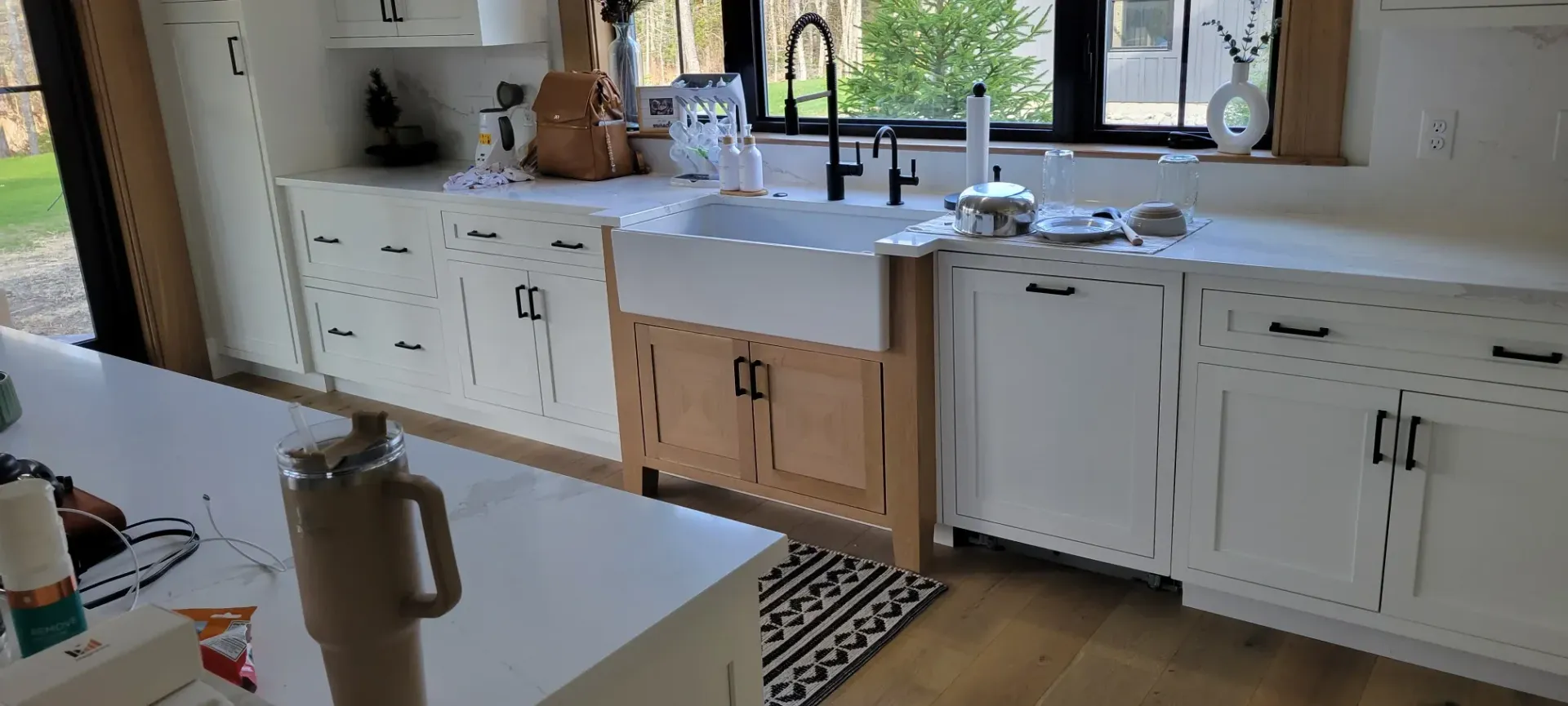 Bright kitchen with white cabinets, island, sink under a window, and countertop appliances
