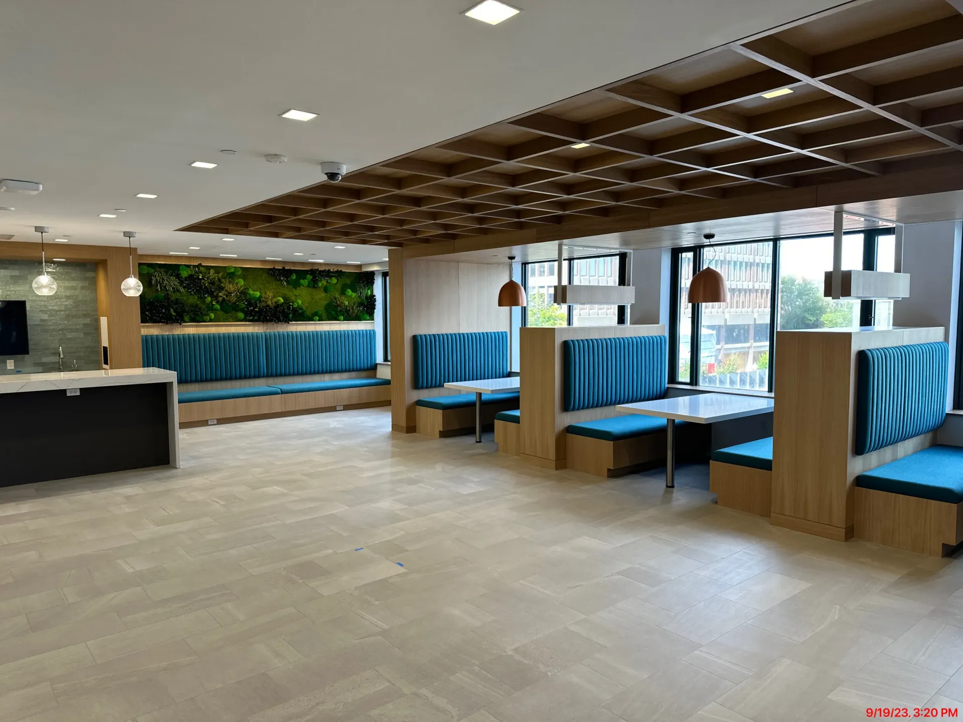 Empty modern restaurant interior with blue booth seating, wood accents, and large windows
