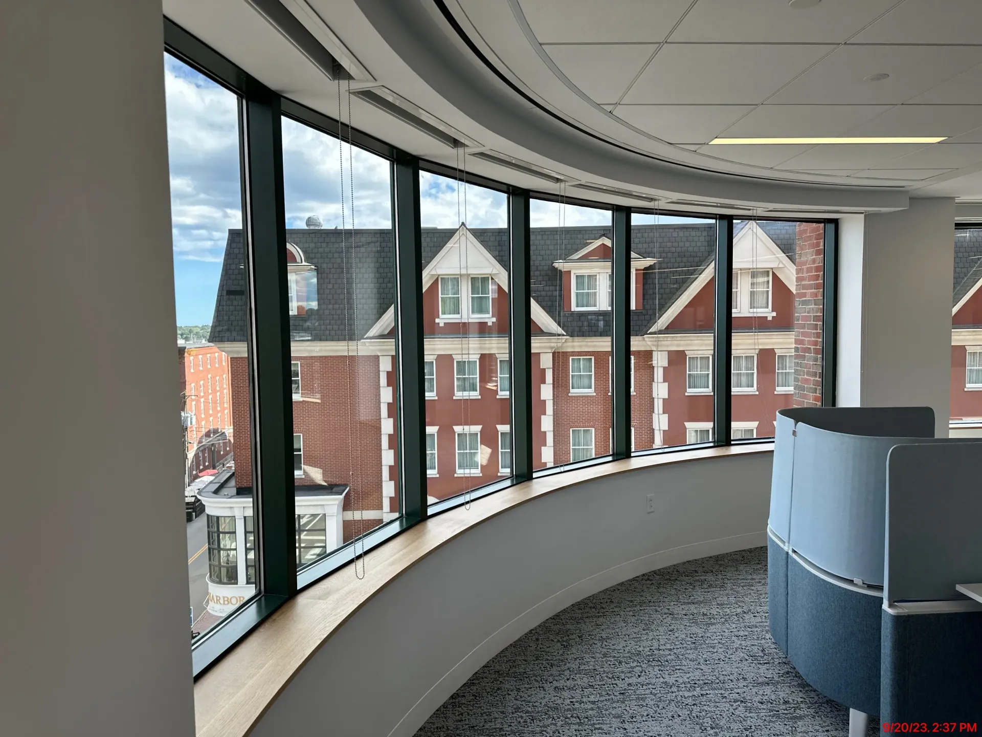 Curved office hallway with large windows overlooking brick buildings and a carpeted floor