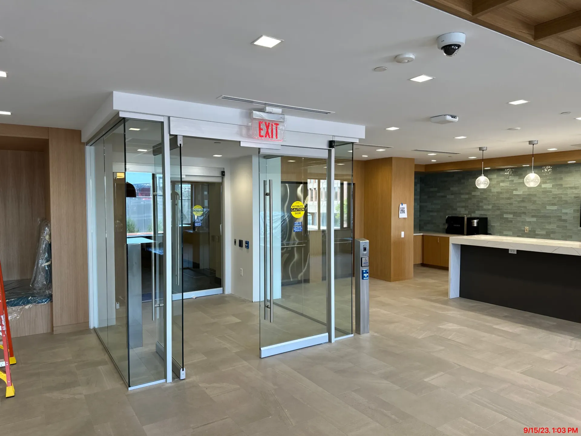 Building lobby with glass entry doors, reception counter, and beige tiled floor