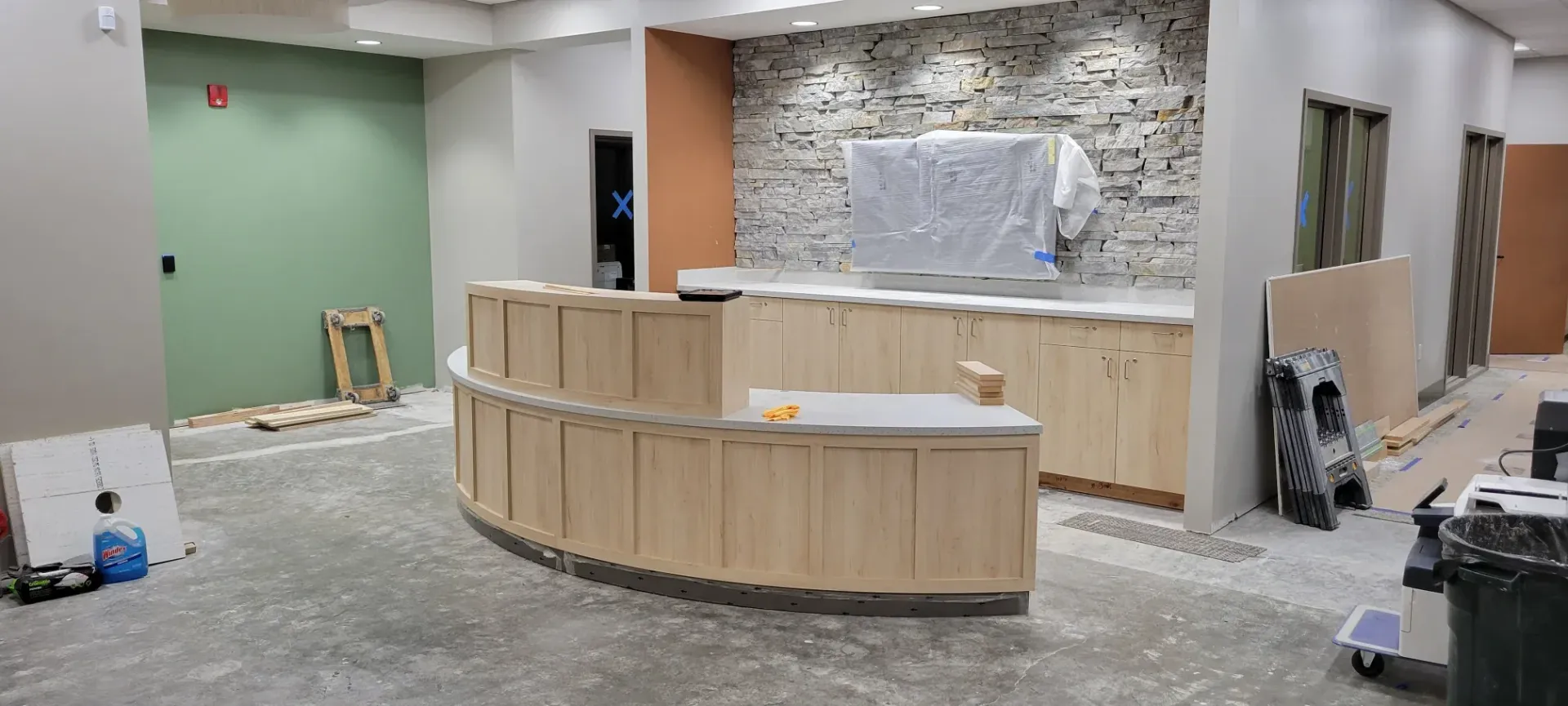 Construction site interior with curved wooden reception desk and unfinished walls under renovation
