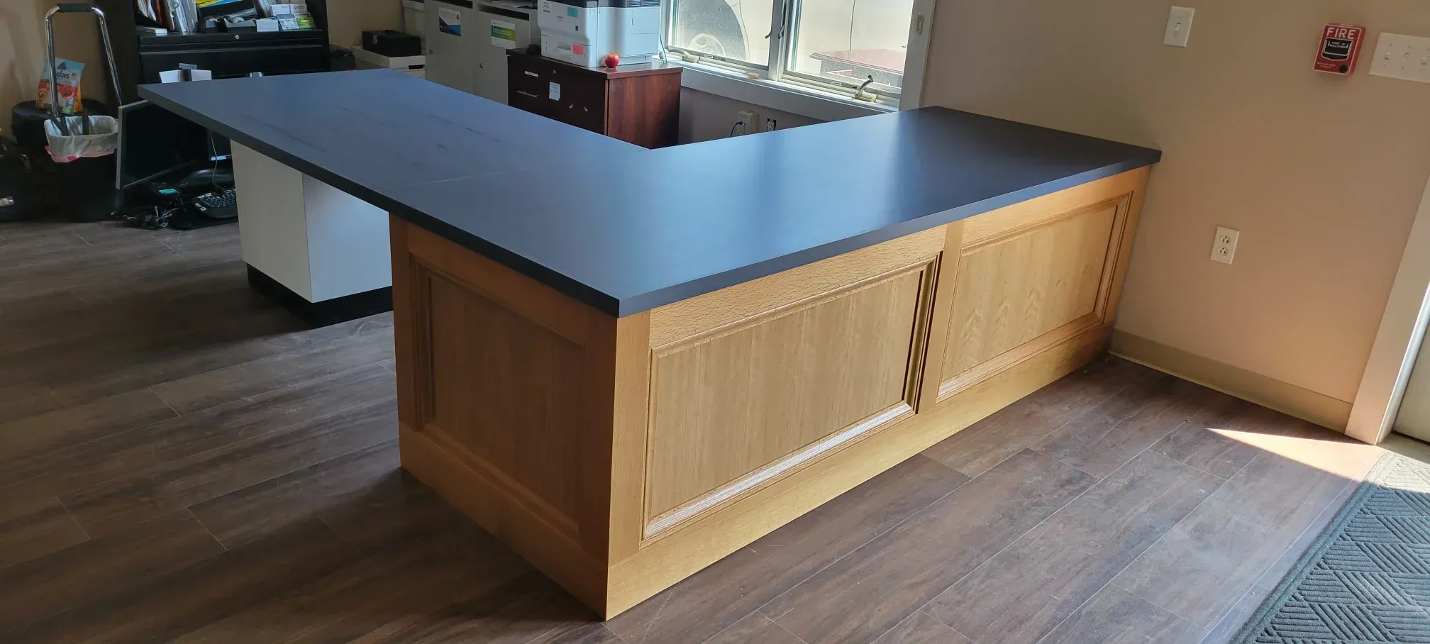 Kitchen island with dark countertop and light wood base in a sunlit room