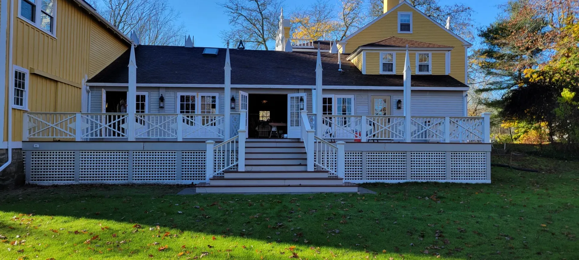 White two-story house with porch, stairs, and railing, viewed from the front yard