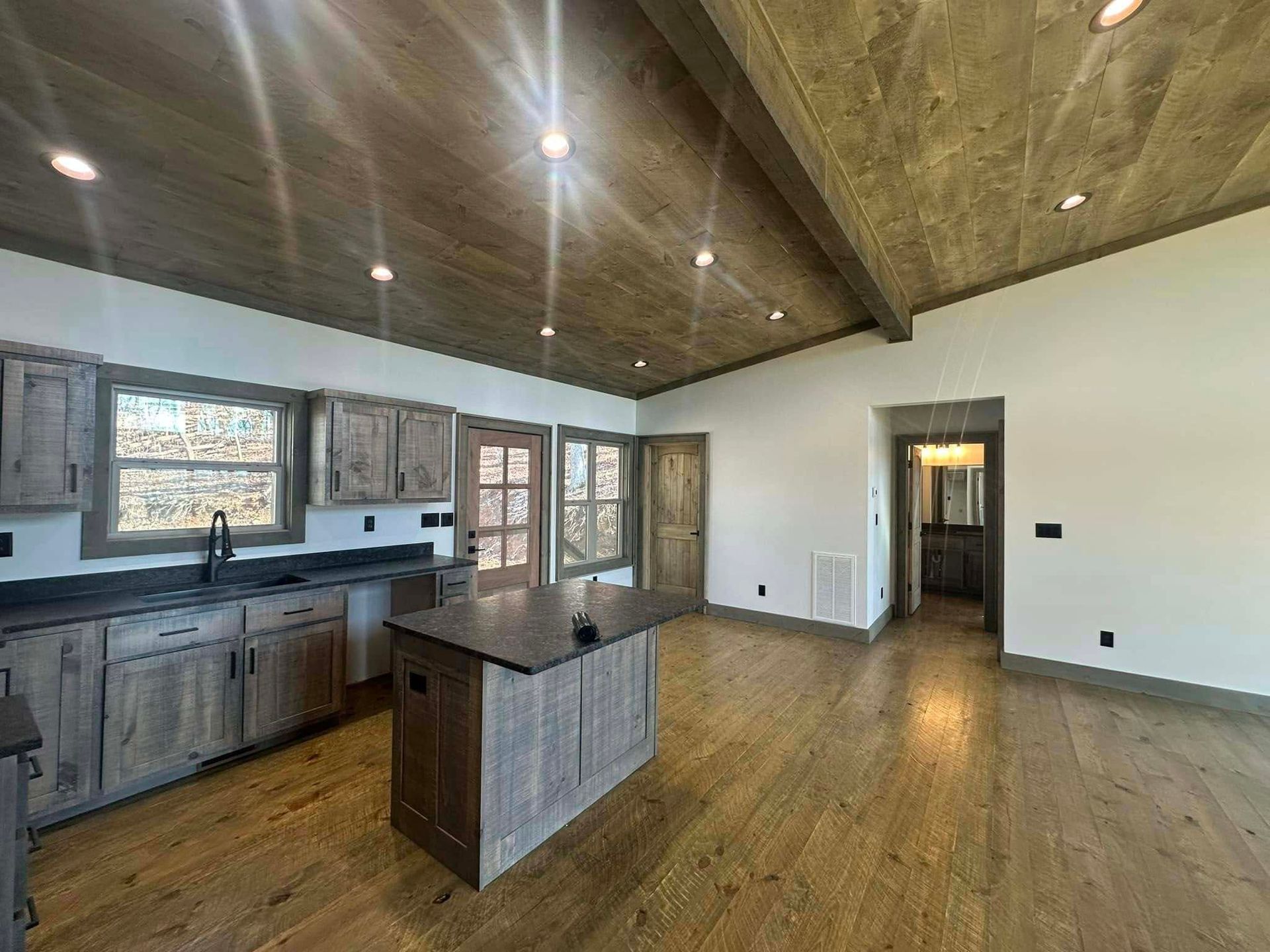 Open-concept kitchen and living area with wood floors, island, and vaulted ceiling with recessed lights