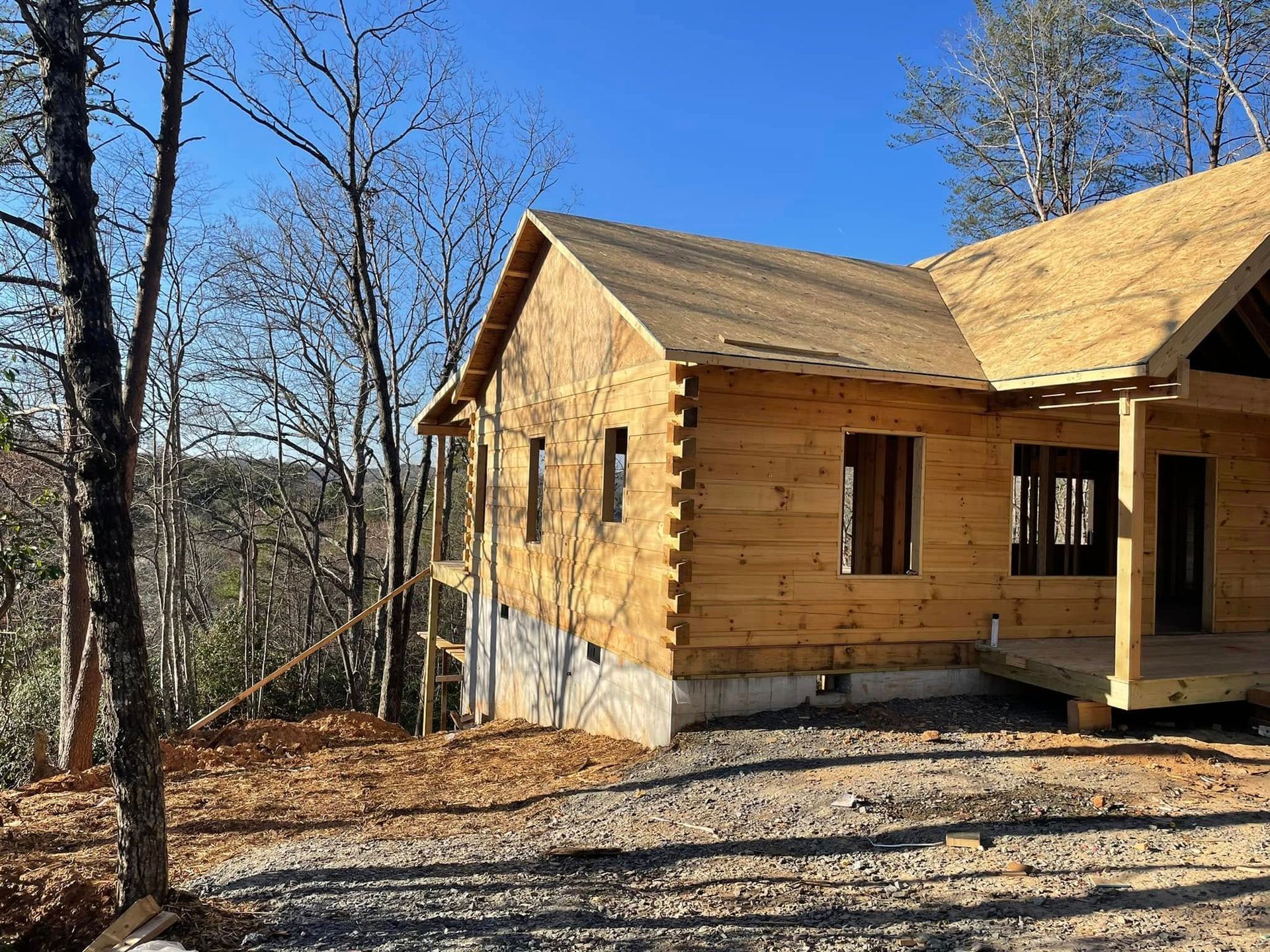 Wooden house under construction in a wooded area on a sunny day