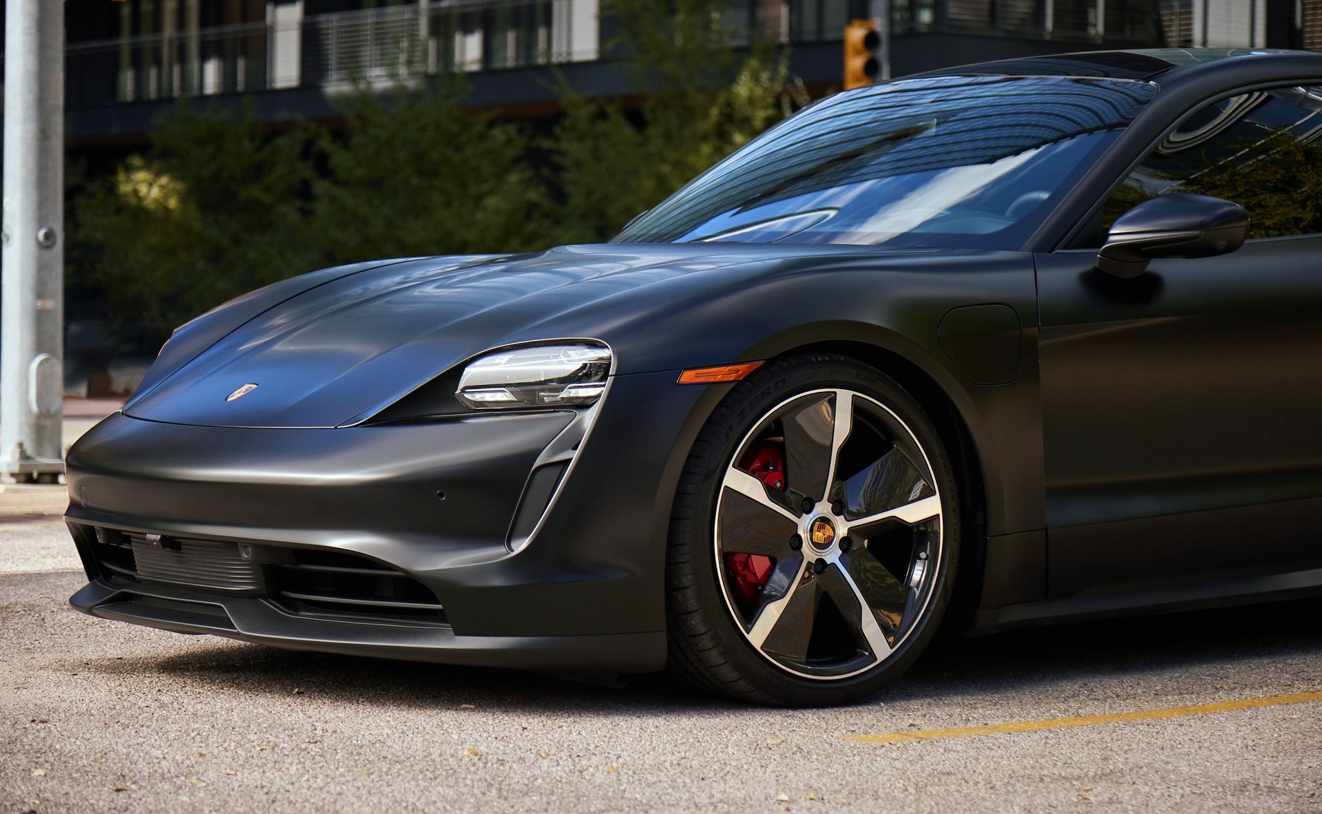 Black Porsche Taycan electric car parked on a city street.